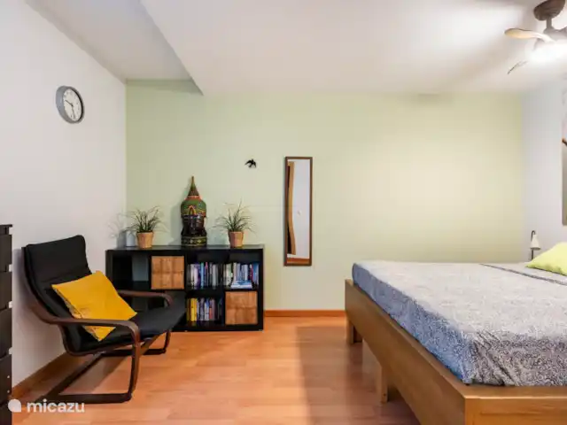 Location de Vacances Espagne, Costa del Sol, Mijas Costa, appartement - Sense-sol Lit double, commode, tables de chevet, bibliothèque et fauteuil. Chambre fraîche avec ventilateur de plafond. Photo prise sous un angle différent.