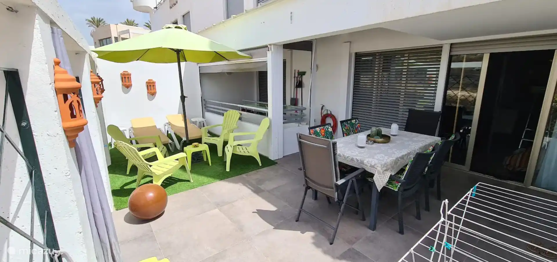 Terrasse
Terrasse sud-ouest avec table pour 6 personnes, coin salon partiellement couvert sur gazon artificiel. Accès par le salon, la chambre principale et les escaliers à la troisième chambre et au parking privé. Séchoir et parasol