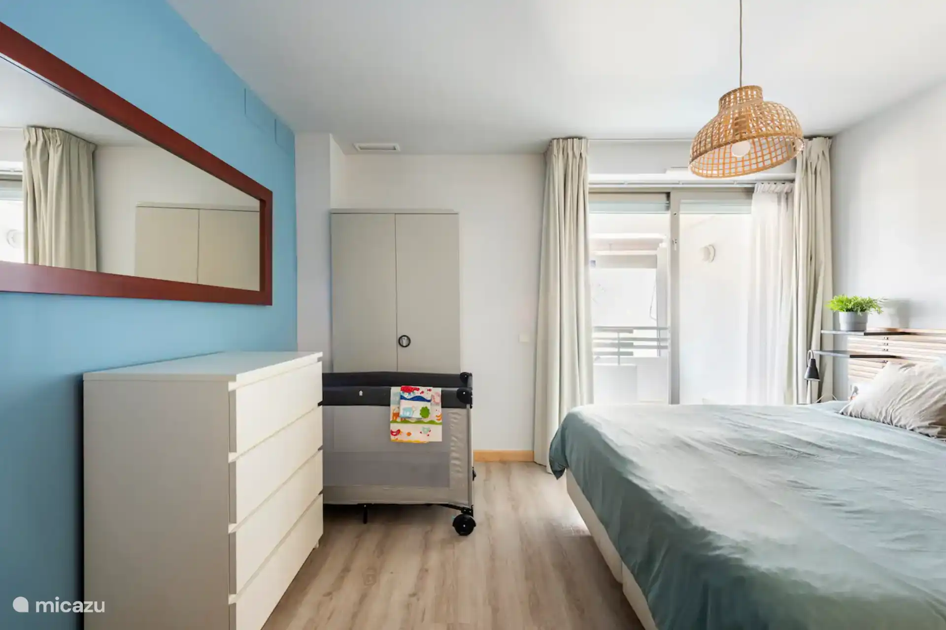 Chambre parentale avec lit double, commode et passage vers la terrasse. Option pour lit bébé de camping. Photo prise sous un angle différent. Ameublement confortable et pratique.