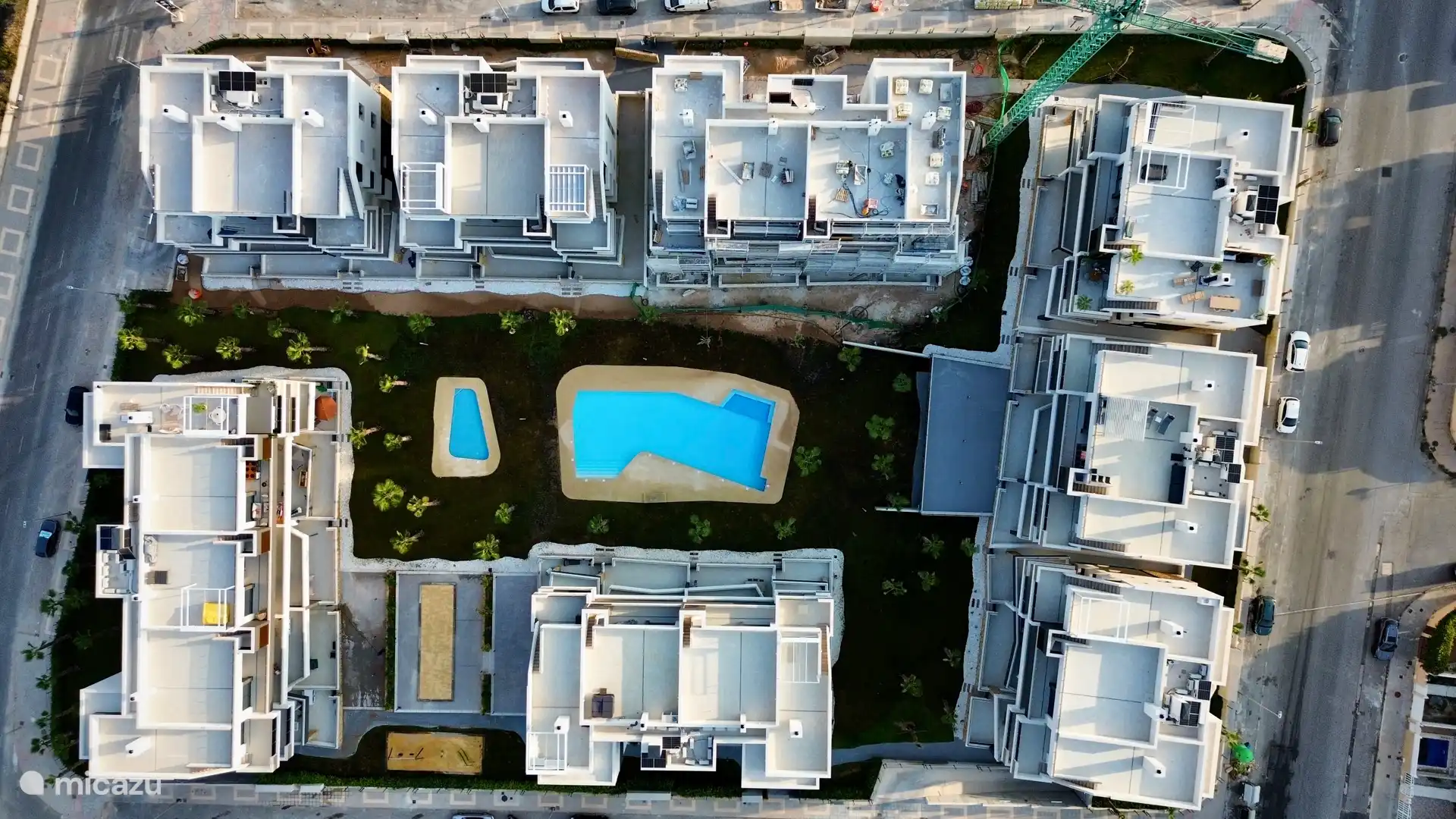 Luchtfoto van het complex met twee zwembaden, groene tuinen en ruime terrassen. Een modern resort voor ontspanning en plezier.