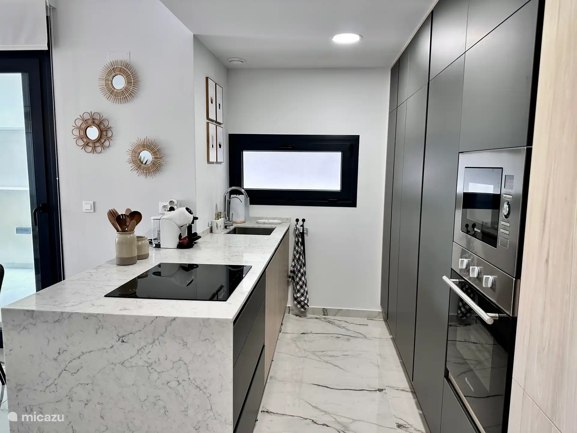 Strakke designkeuken met kookeiland, oven, inductie en alle moderne apparatuur. Compleet ingericht voor een zorgeloos verblijf.