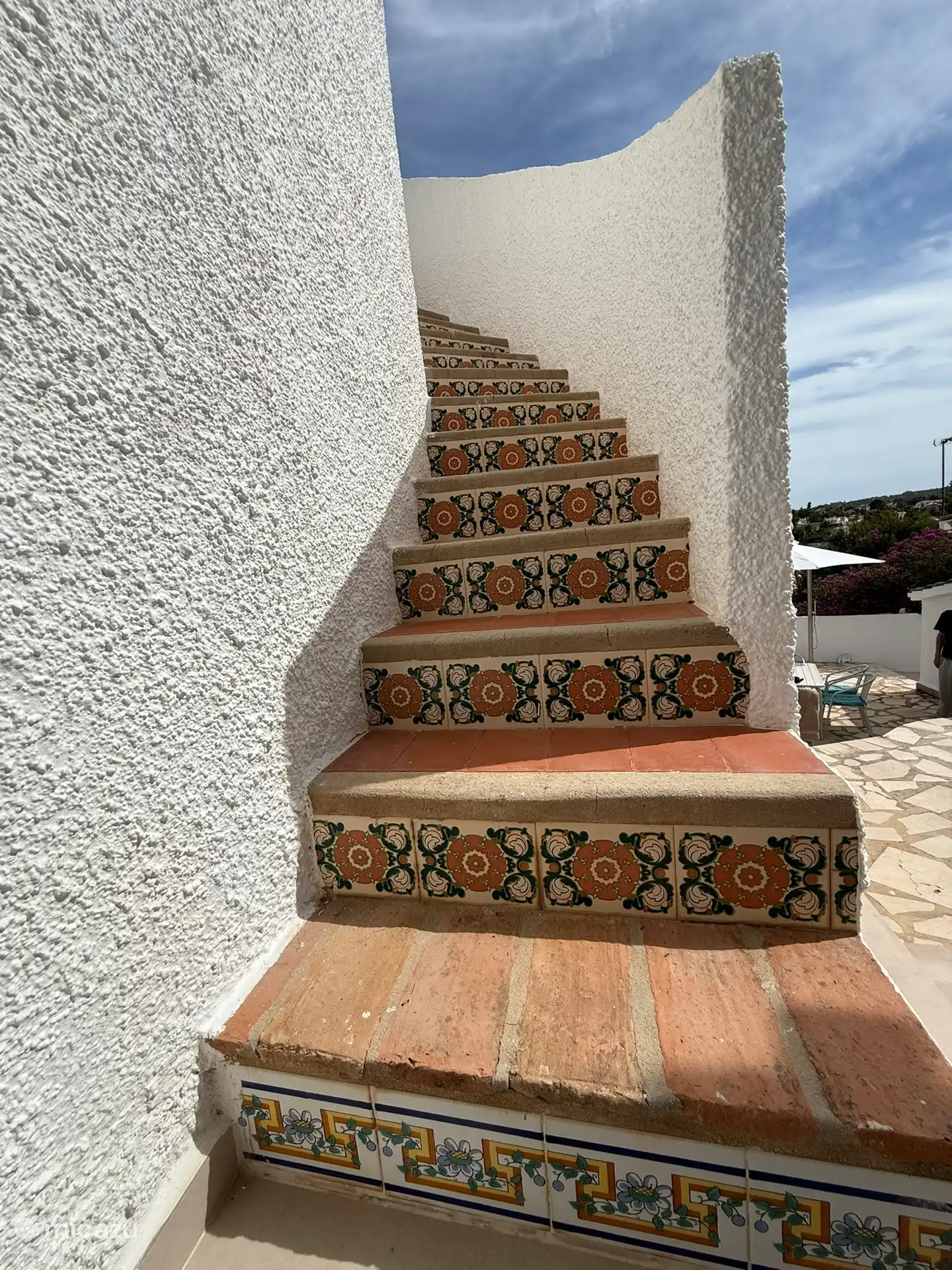Escalera exterior que conecta la planta baja y la superior, con azulejos españoles a tus pies.