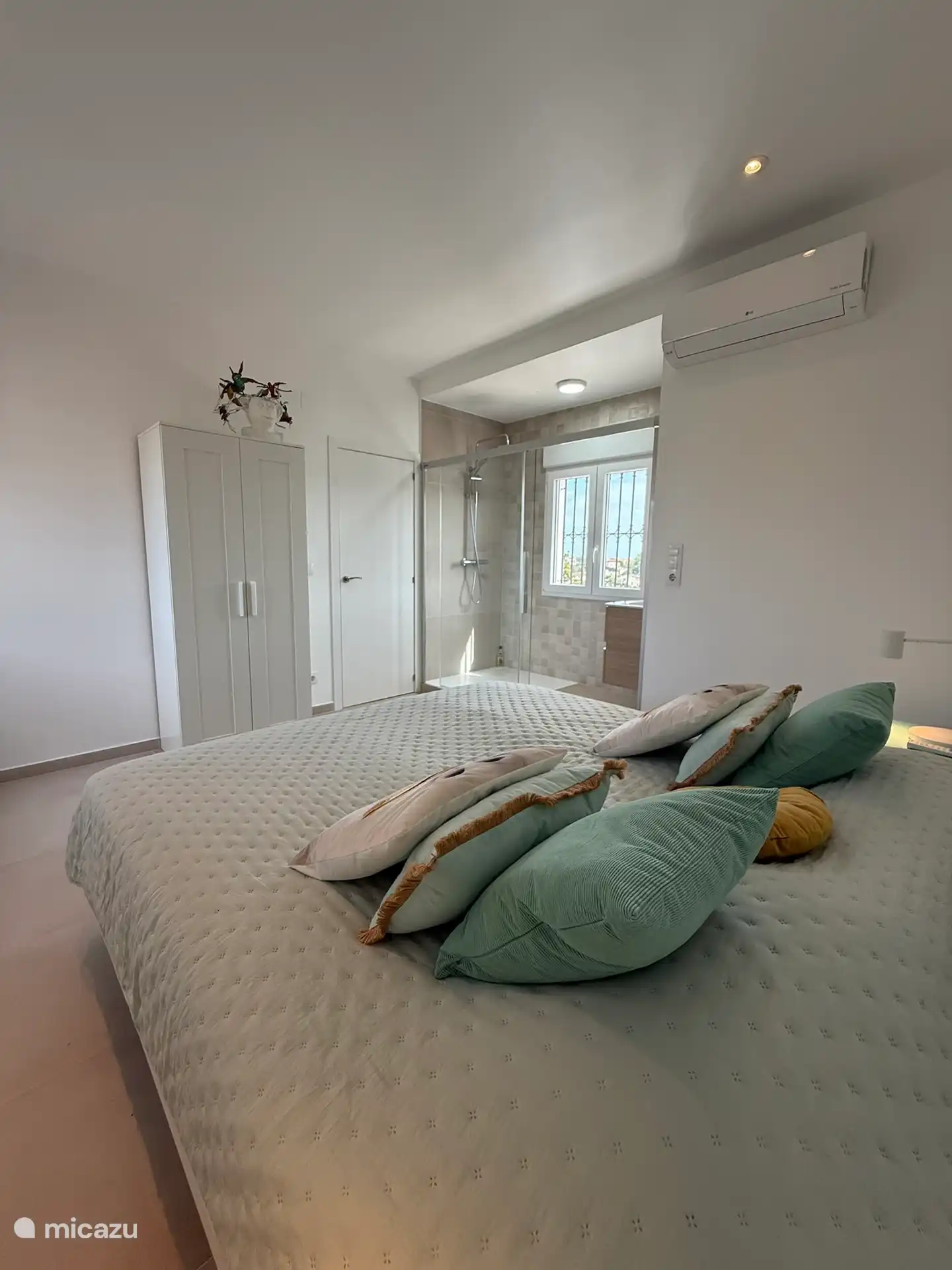 Dormitorio 3 en la primera planta con vistas al baño en suite y mucha luz a través de ventanas a ambos lados.