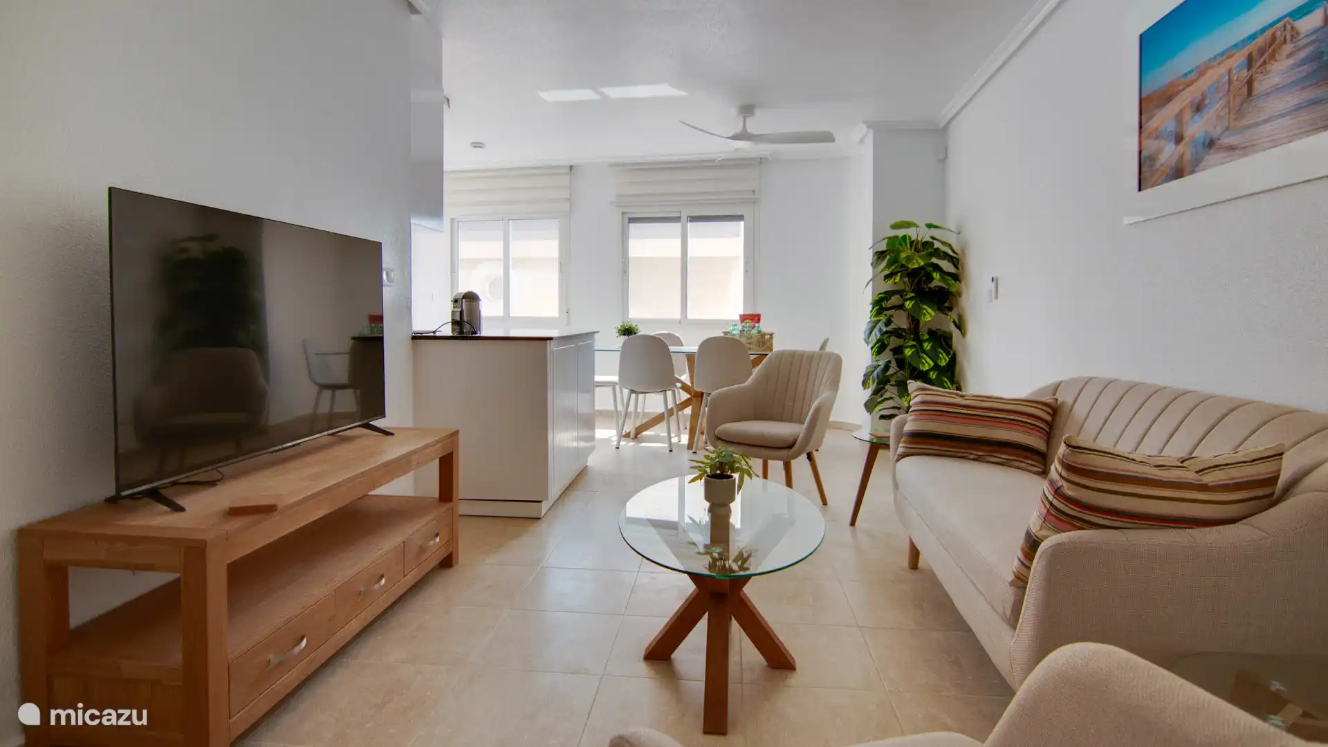 Bright living room with comfortable sitting area, open kitchen and dining table in the background, ideal for socializing.