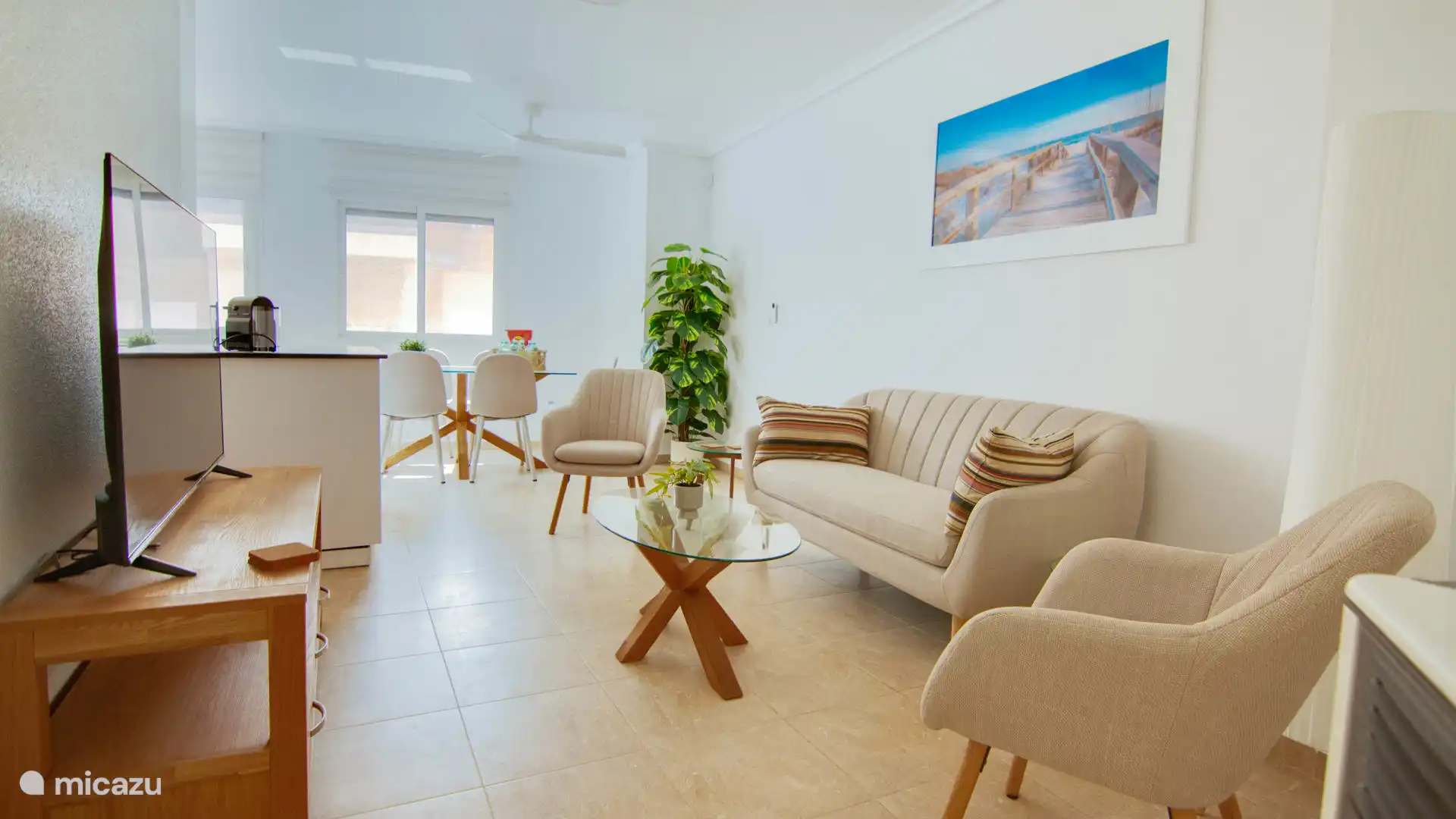 Bright living room with comfortable sitting area, open kitchen and dining table in the background, ideal for socializing.