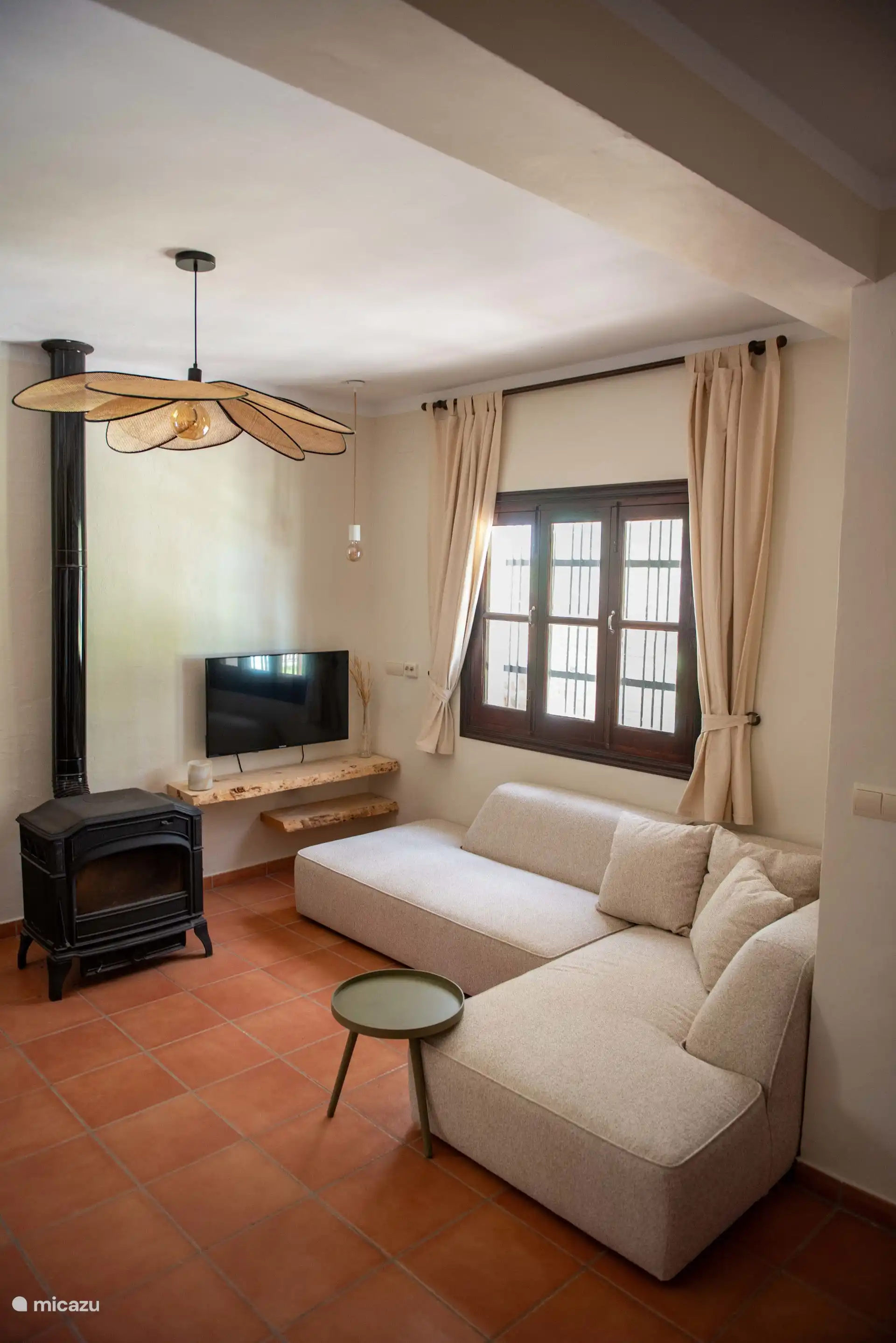 Wohnzimmer mit TV, Sofa und Holzofen