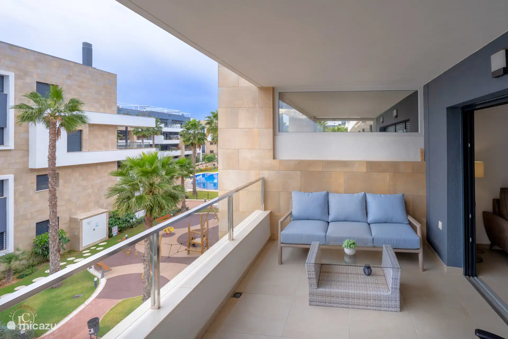 Terrasse avec un coin salon confortable et une vue sur les piscines et une aire de jeux.
