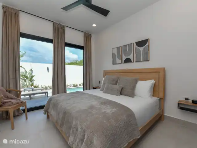 Casa Ruby con piscina privada en Aruba, Norte, Noord - casa vacacional Dormitorio con cama King size, TV, aire acondicionado y vista a la piscina