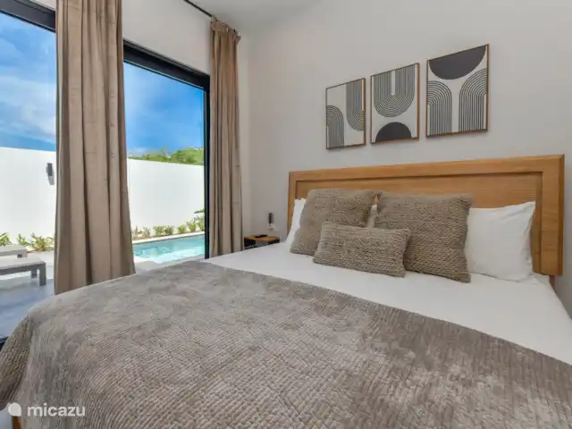 Casa Ruby con piscina privada en Aruba, Norte, Noord - casa vacacional Dormitorio con cama King size, TV, aire acondicionado y vista a la piscina