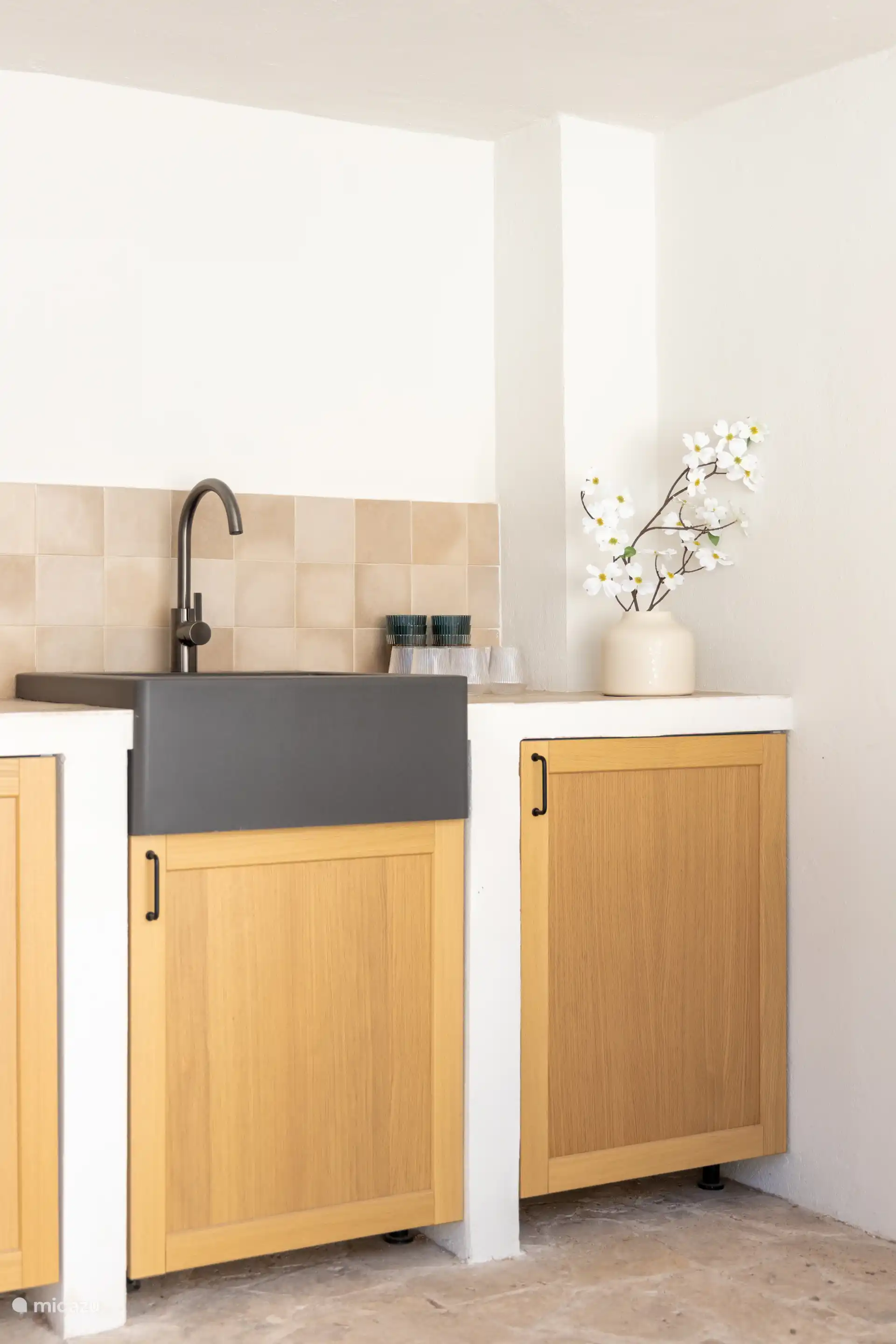 Überdachte Außenküche mit Kühlschrank und Plastikgläsern.