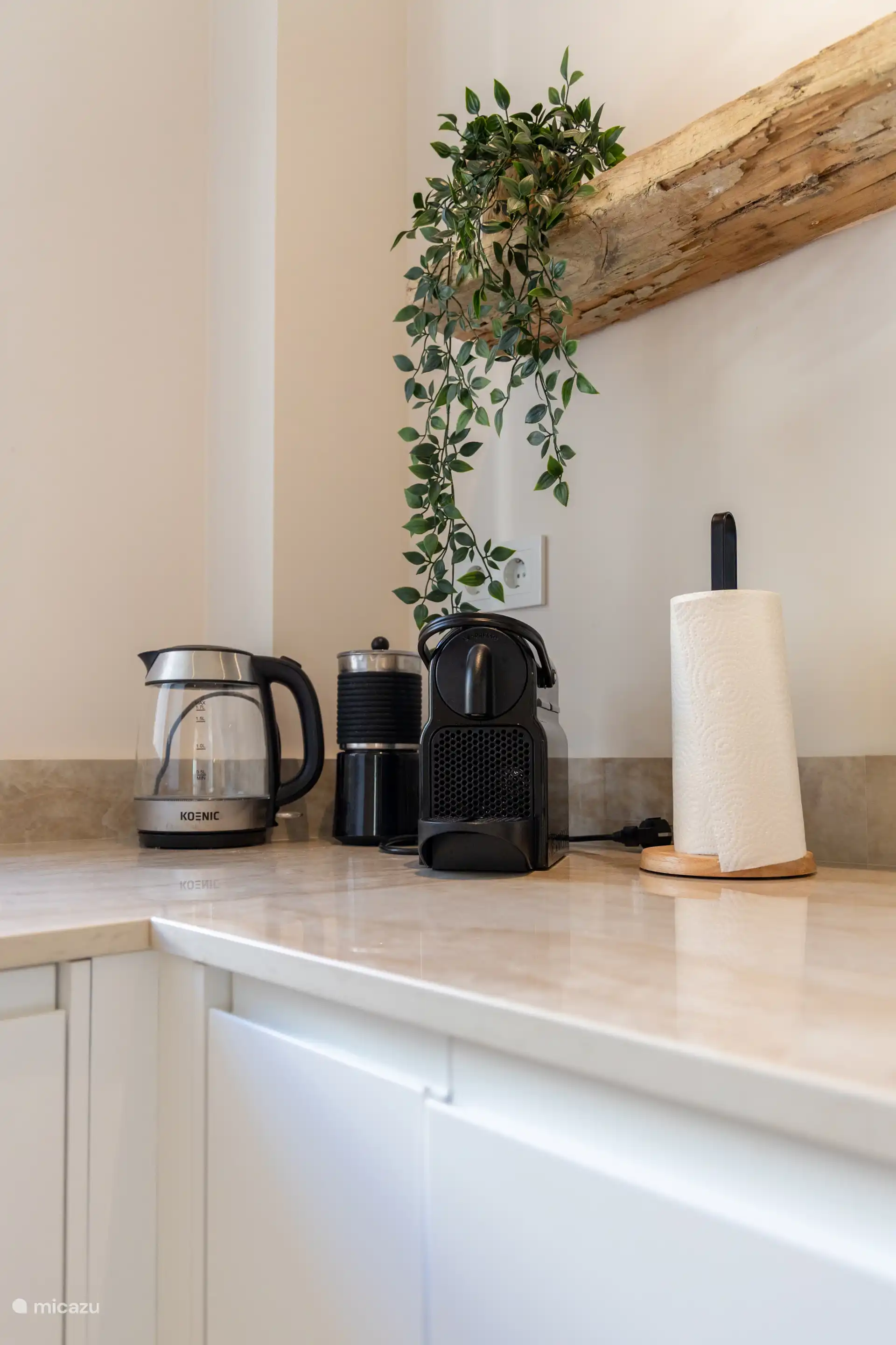 Eine Kaffeemaschine mit Milchaufschäumer und ein Wasserkocher sind ebenfalls vorhanden.