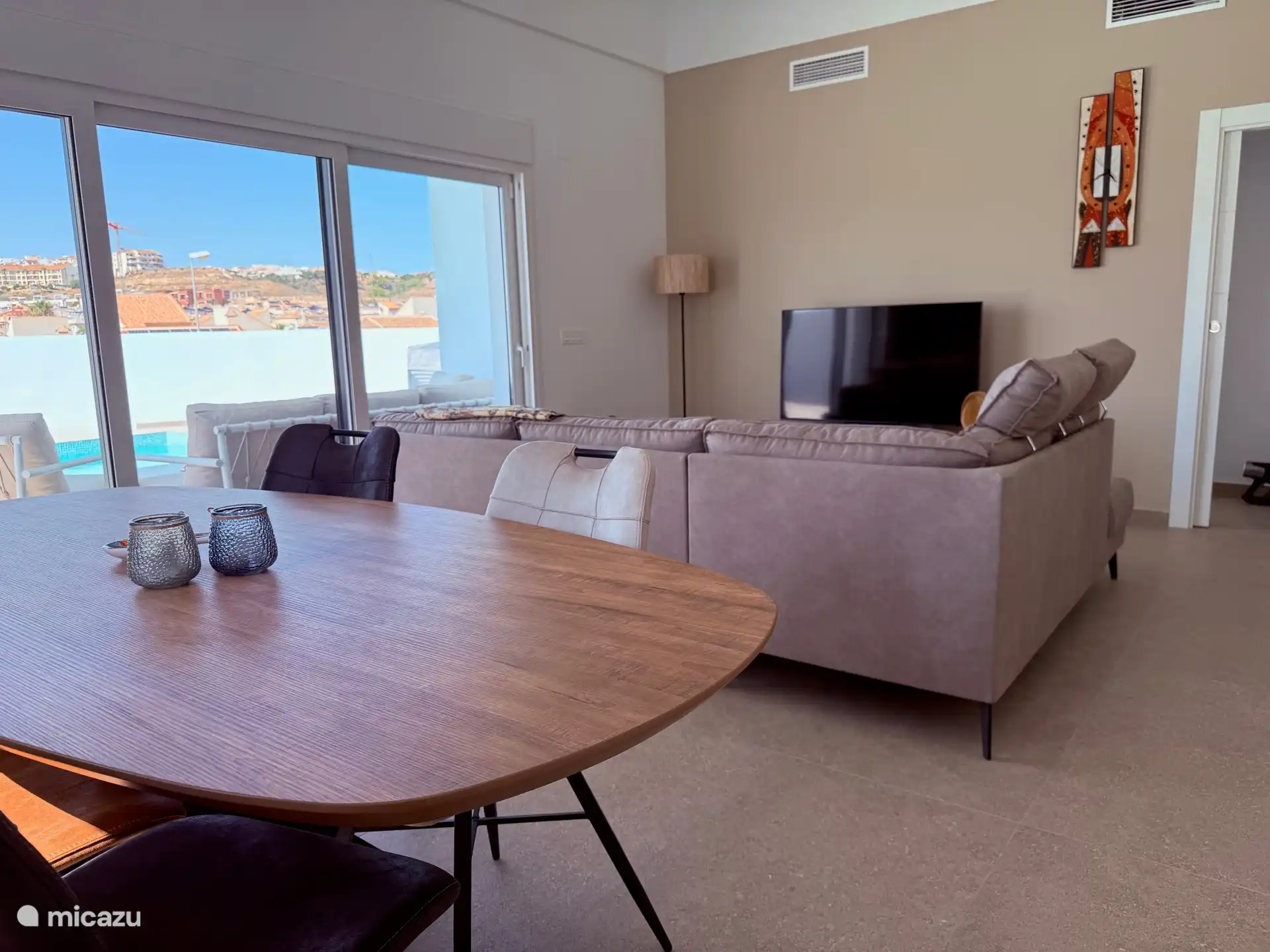 Geräumiges Wohnzimmer mit Smart-TV und Essbereich, hohe Decken runden das geräumige Gefühl ab.