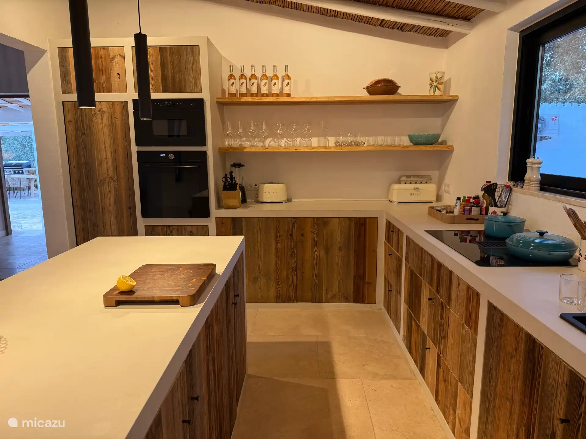 Una cocina está equipada con todas las comodidades: cafetera, tostadora, sandwichera, hervidor de agua, airfryer, juego de sartenes, sartenes creuset, prensa de naranjas, nevera, congelador, microondas / horno.