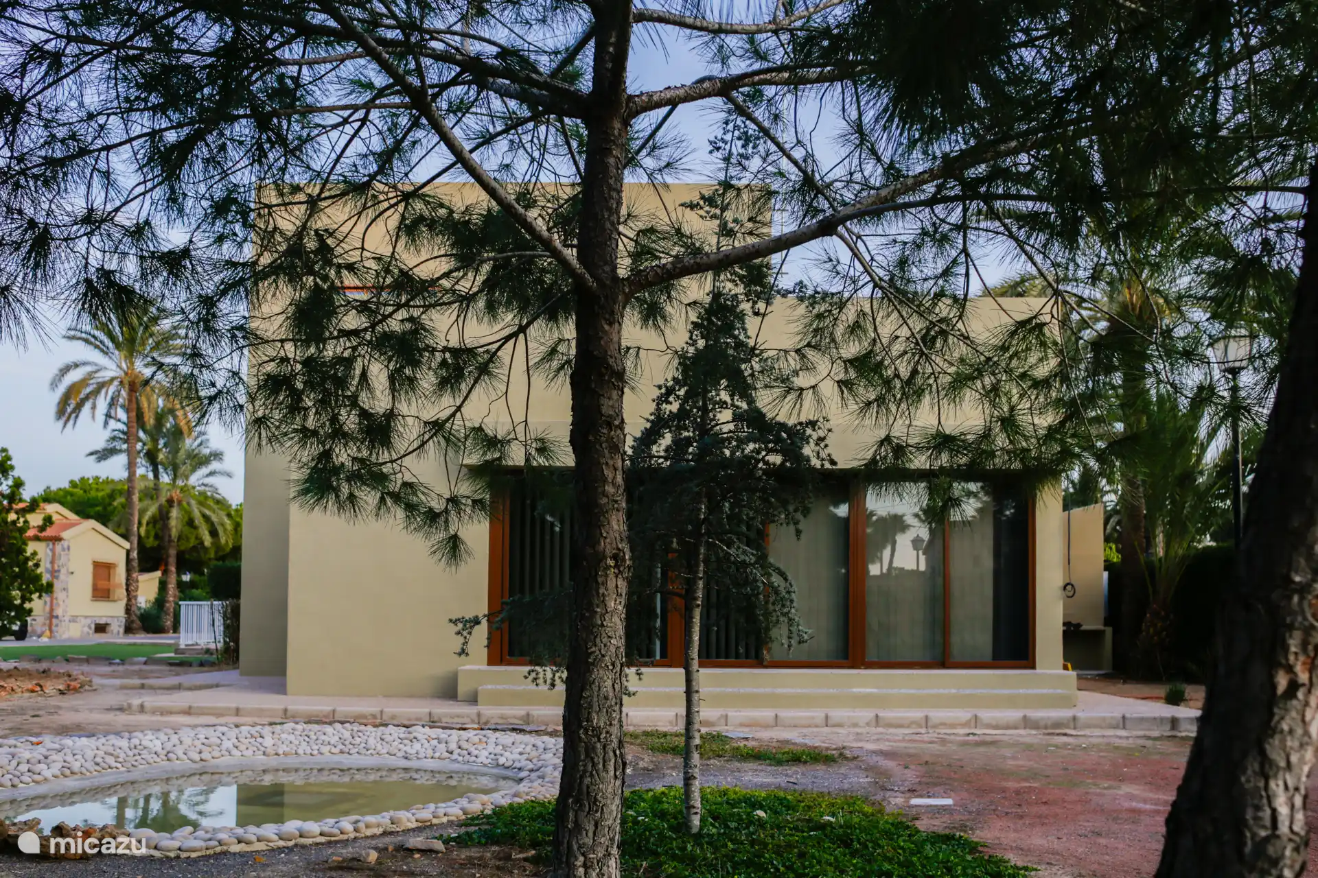 Achteraanzicht van het huis, vijver en glas van de hoofdruimte.