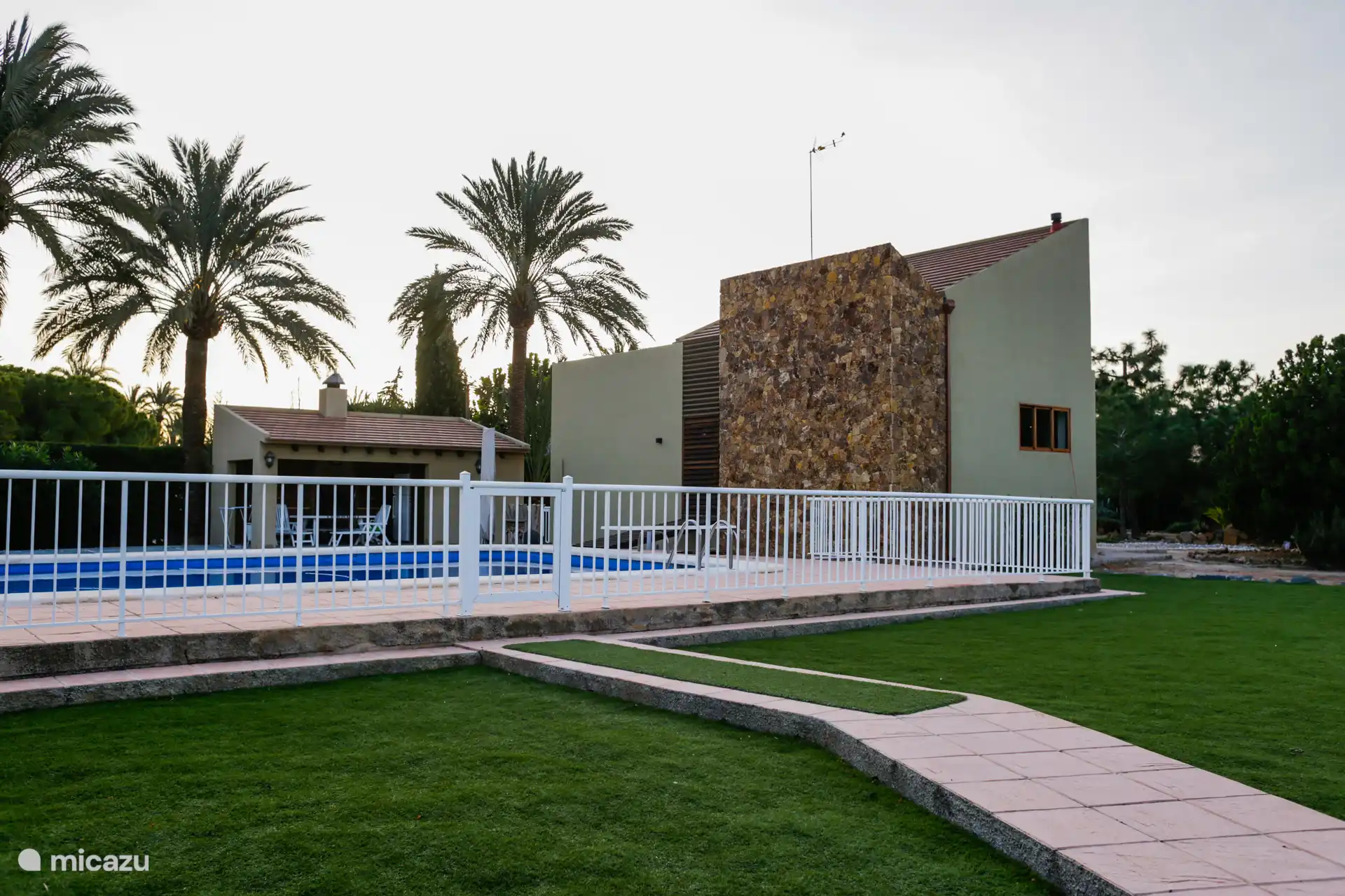 Uitzicht op het zwembad en het barbecuegebied, vanaf het tuingrasveld.