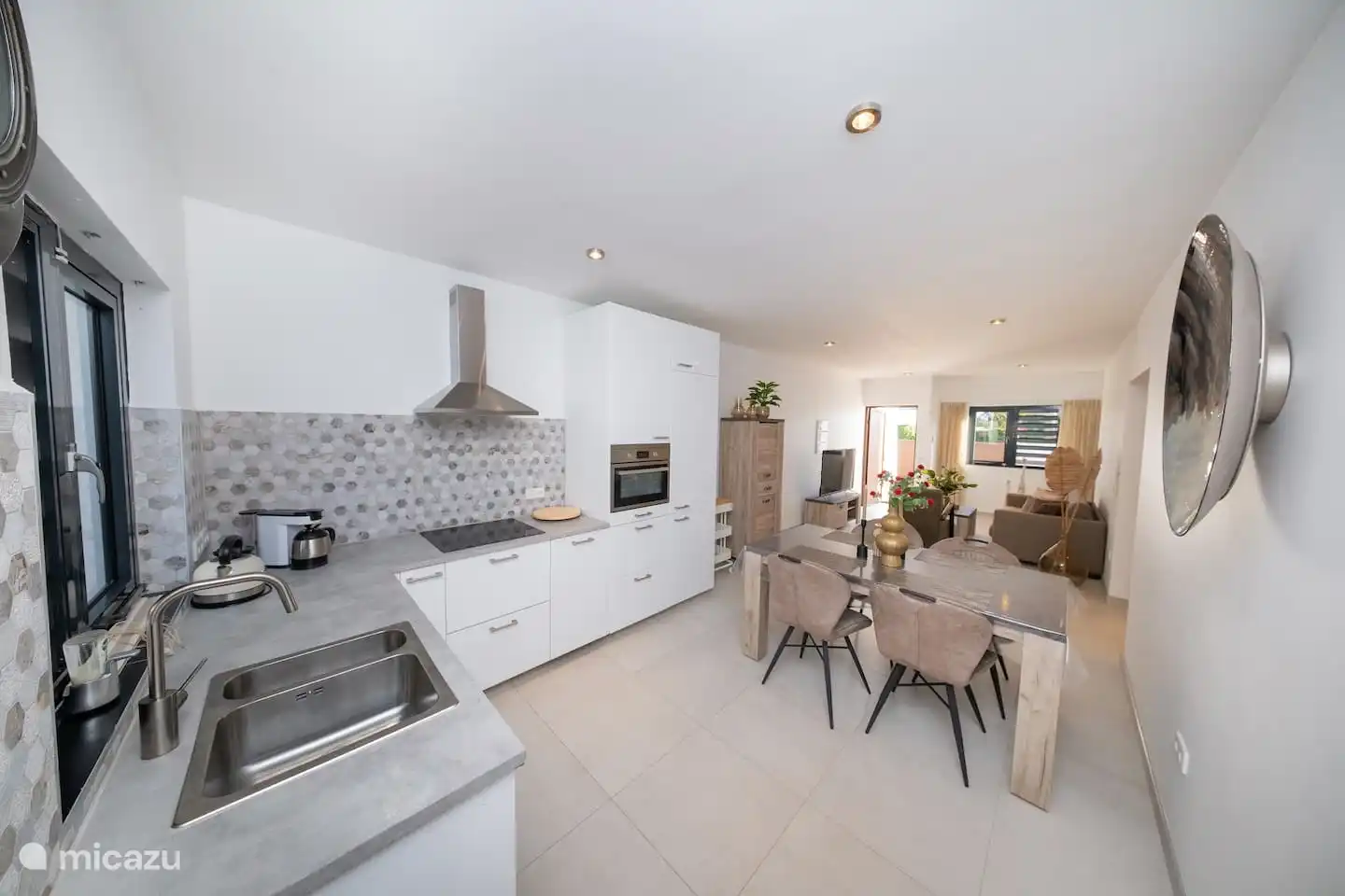 Keuken met inductie kookplaat, combimagnetron, koel- vries kast, vatwasser en ruime keukengerei.