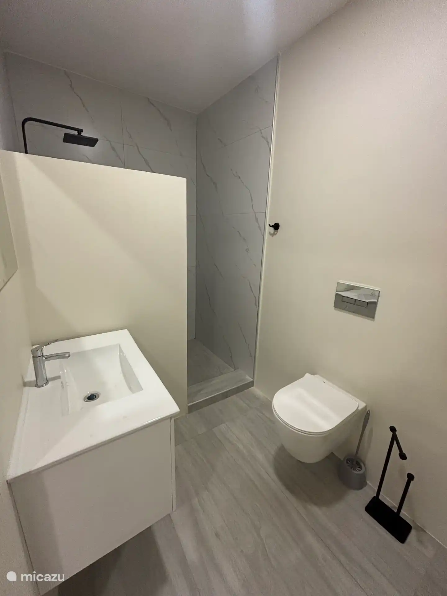 Modernes Badezimmer mit Hängetopf, begehbarer Dusche, Waschbecken mit Spiegel, Fön und Steckdose. 