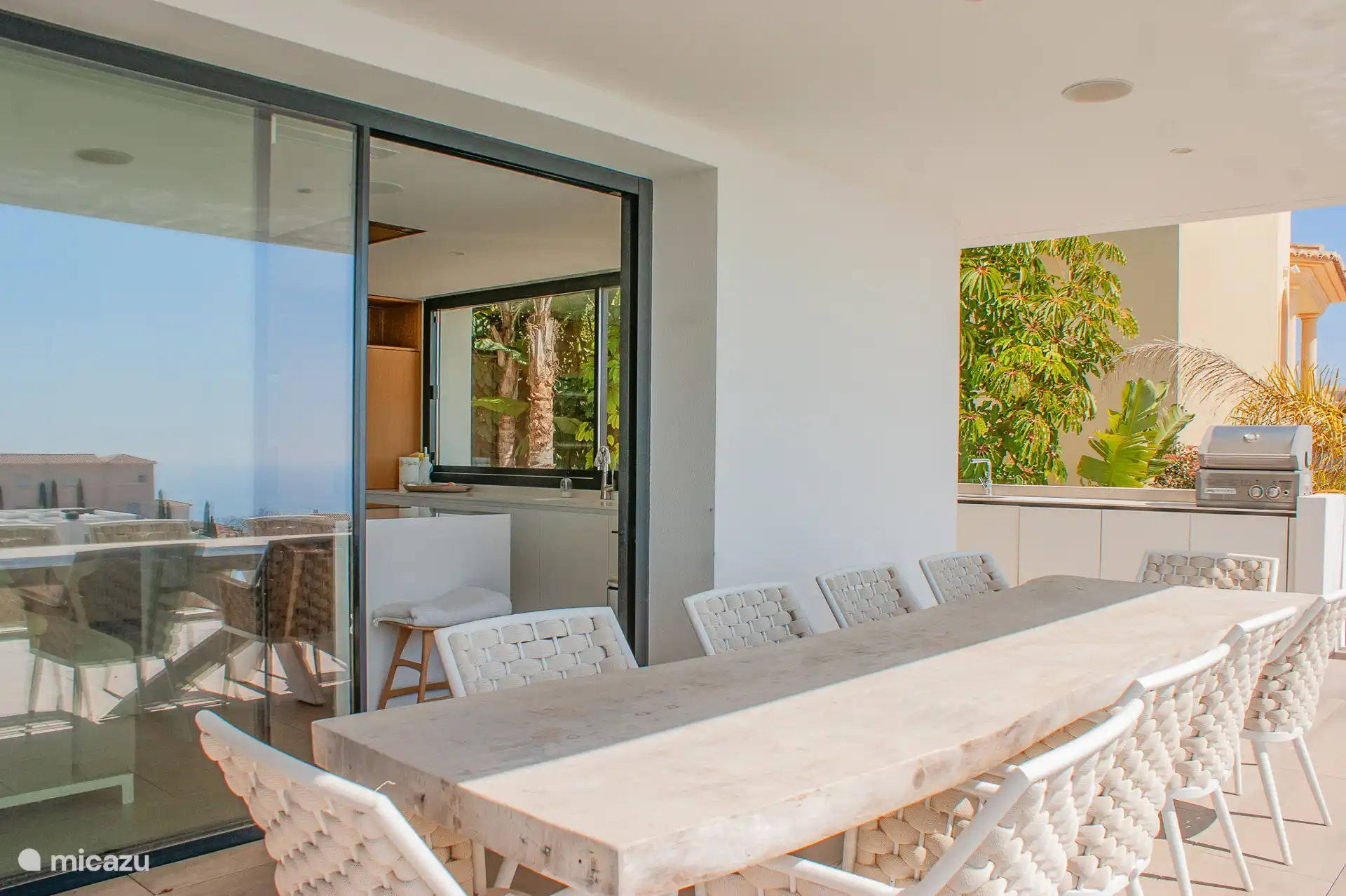 Große überdachte Terrasse mit Außenküche und einem Esstisch für zehn Personen