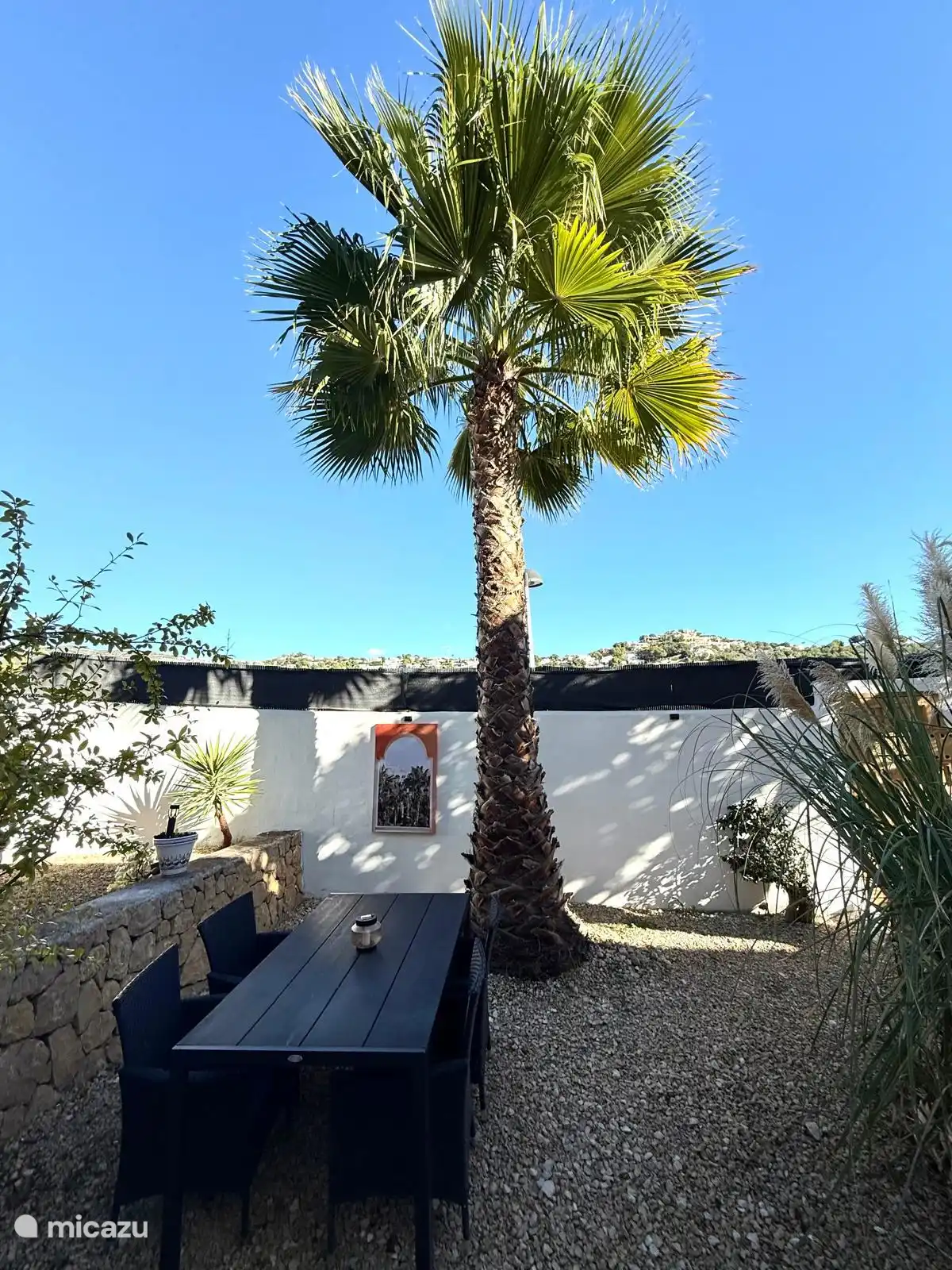 Jardin espagnol avec des transats en palmiers et une table à manger.