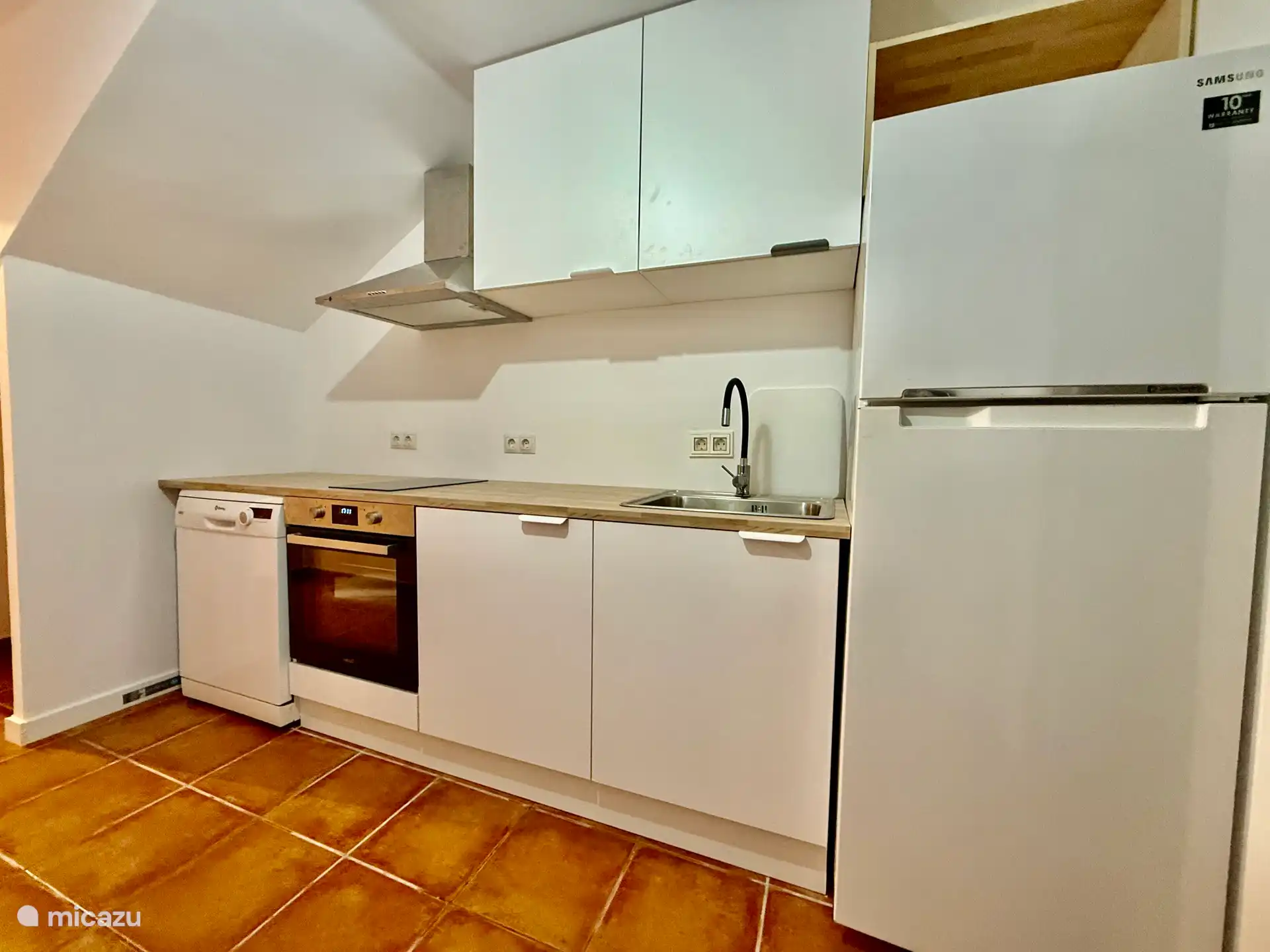 Küche mit Heißluftfritteuse, Mikrowelle, Ofen, Wasserkocher, Geschirrspüler, Gefriertruhe und Kühlschrank.