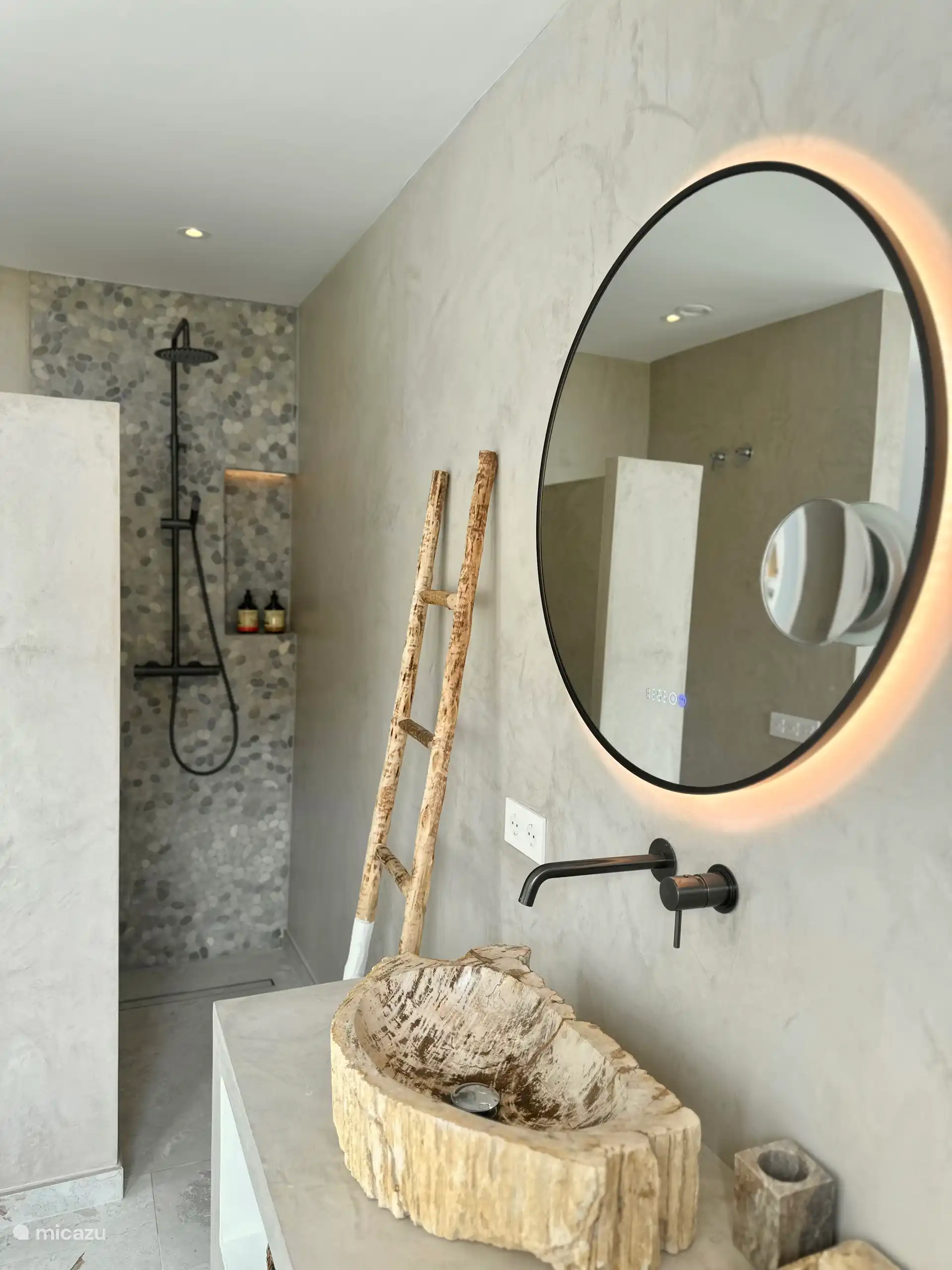 La douche ouverte donne suffisamment d’intimité car elle est placée dans le coin mais s’intègre dans l’ensemble. À côté de la douche se trouvent les toilettes.