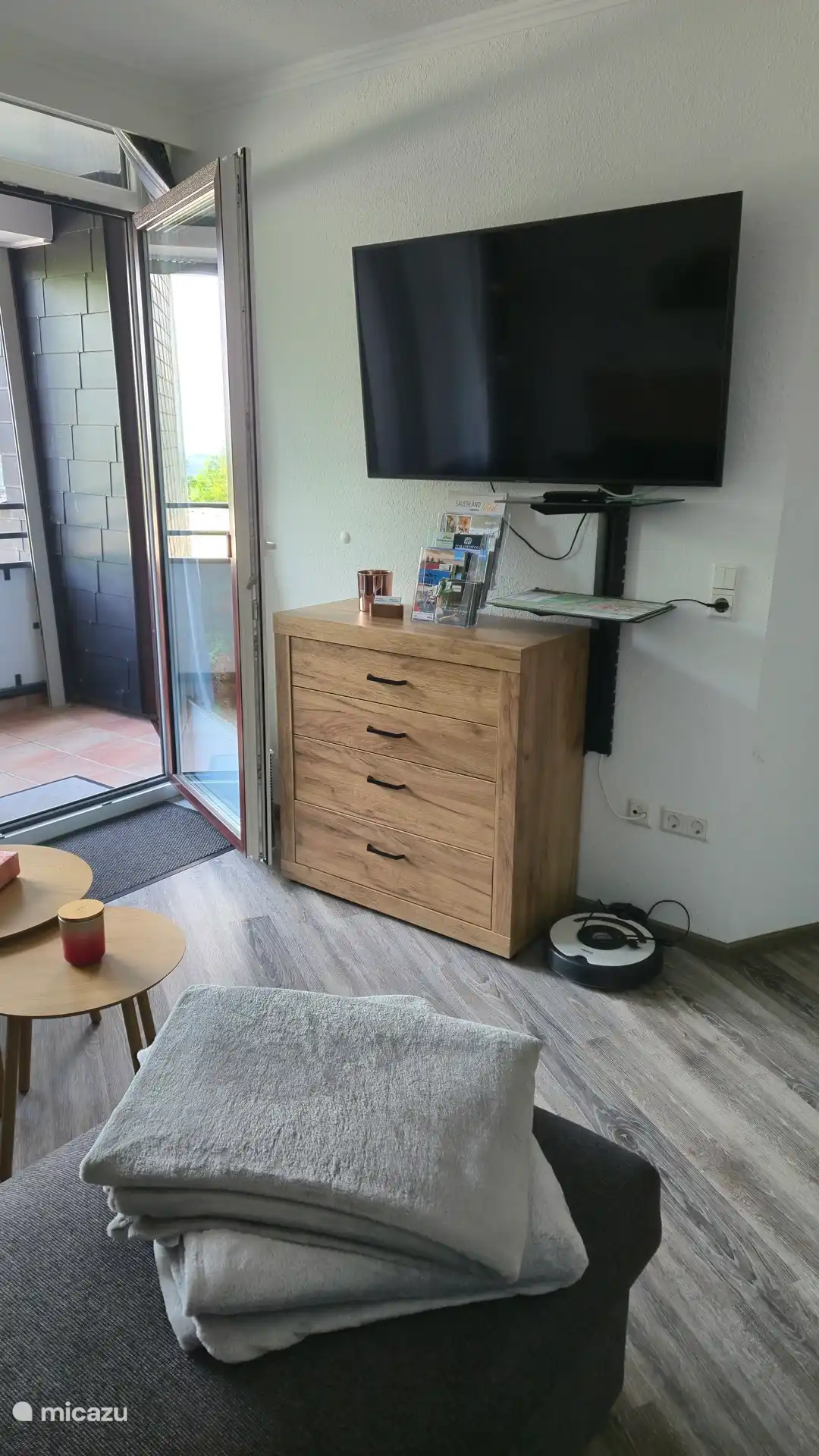 Wohnzimmer mit Smart-TV und direkten Zugang zum Balkon 