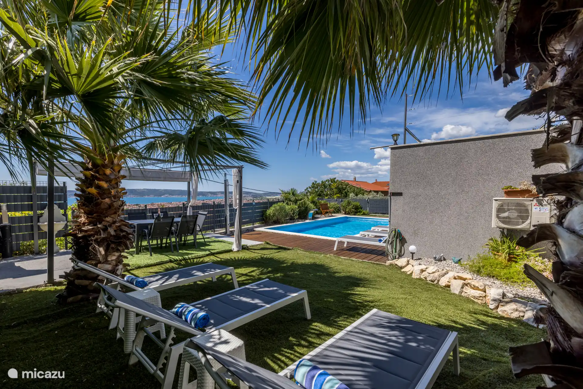 Unter zwei wunderschönen Palmen. Blick von der Liege auf den Pool und das Meer.