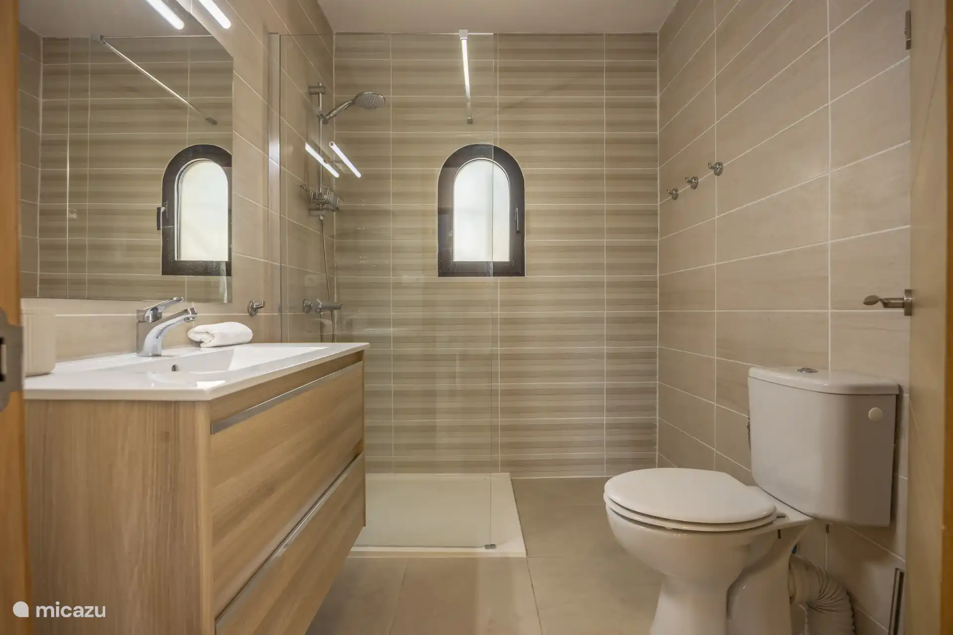 Tweede badkamer met douche, wastafel, en toilet.
