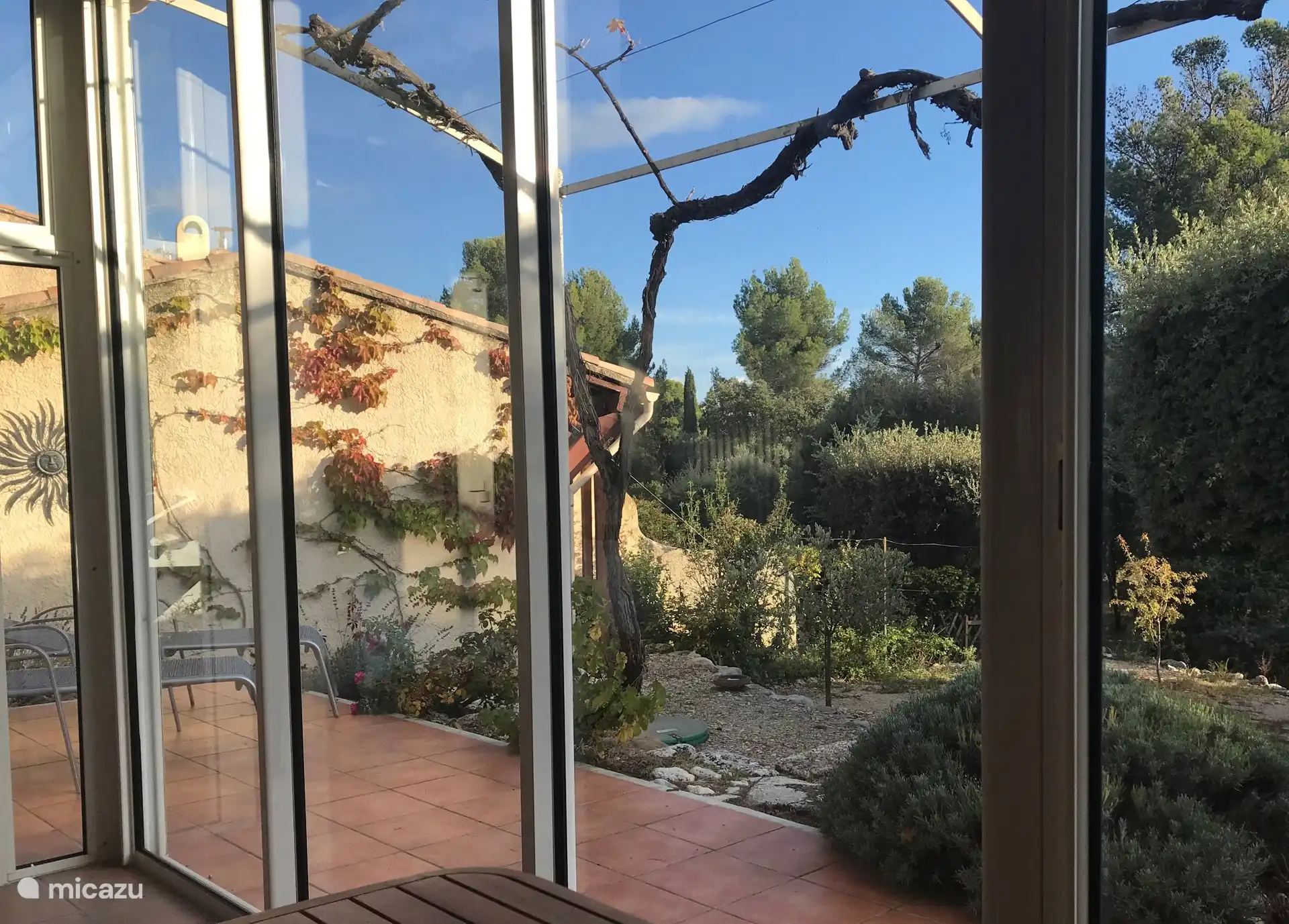 Blick vom Wintergarten über die Terrasse auf die Umgebung Süd. Links die Garage