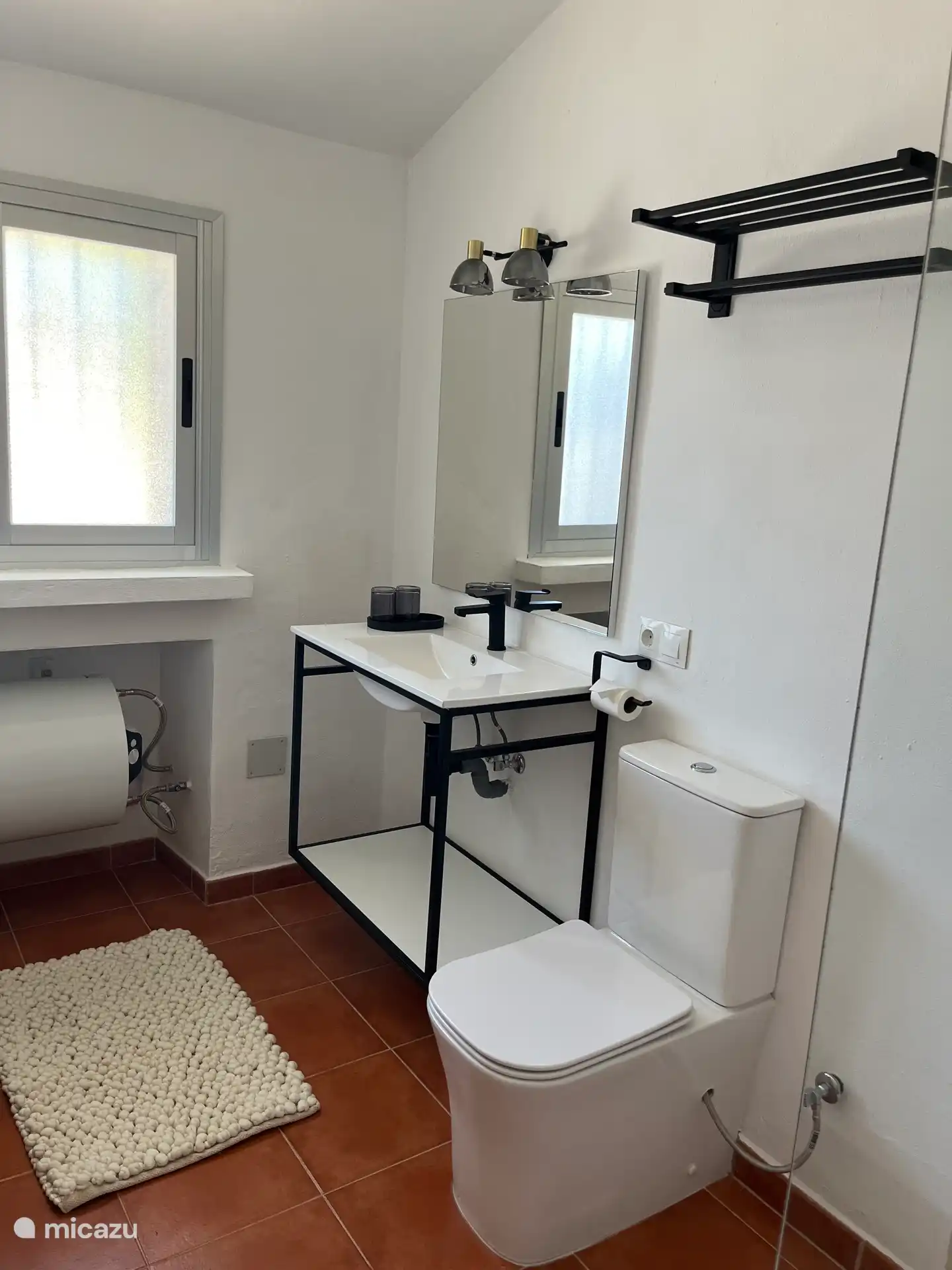 Badezimmer mit Dusche, Waschbecken, Wandregal und Handtüchern ausgestattet