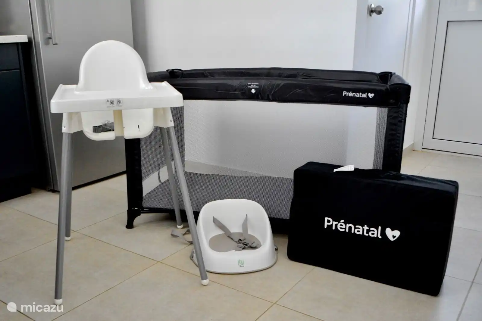 Ein Babybett mit zusätzlicher Matratze und Bettwäsche, Hochstuhl und Sitzerhöhung sind vorhanden.