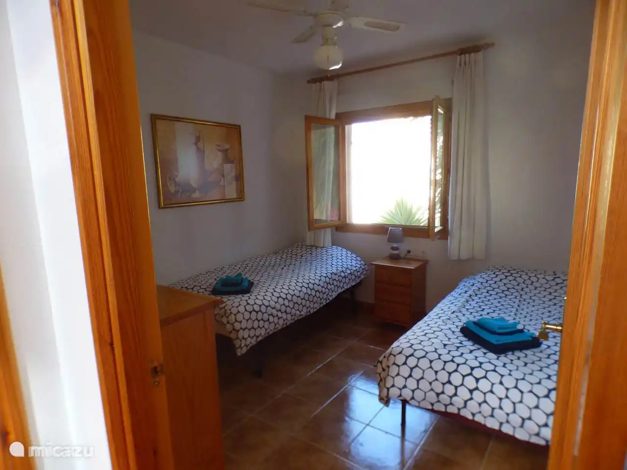 Schlafzimmer im Erdgeschoss mit zwei Einzelbetten, einem Schrank, einem Kleiderschrank und einem Nachttisch. ausgestattet mit Deckenventilator und Klimaanlage. 