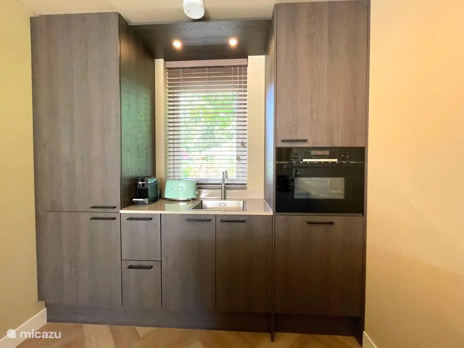 Moderne Küche mit Kombi-Mikrowelle, Quooker, Herd mit Bora, Nespresso, Kühlschrank mit Gefrierfach und Geschirrspüler.