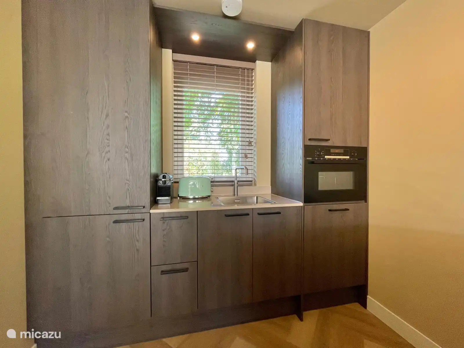 Moderne Küche mit Kombi-Mikrowelle, Quooker, Herd mit Bora, Nespresso, Kühlschrank mit Gefrierfach und Geschirrspüler.