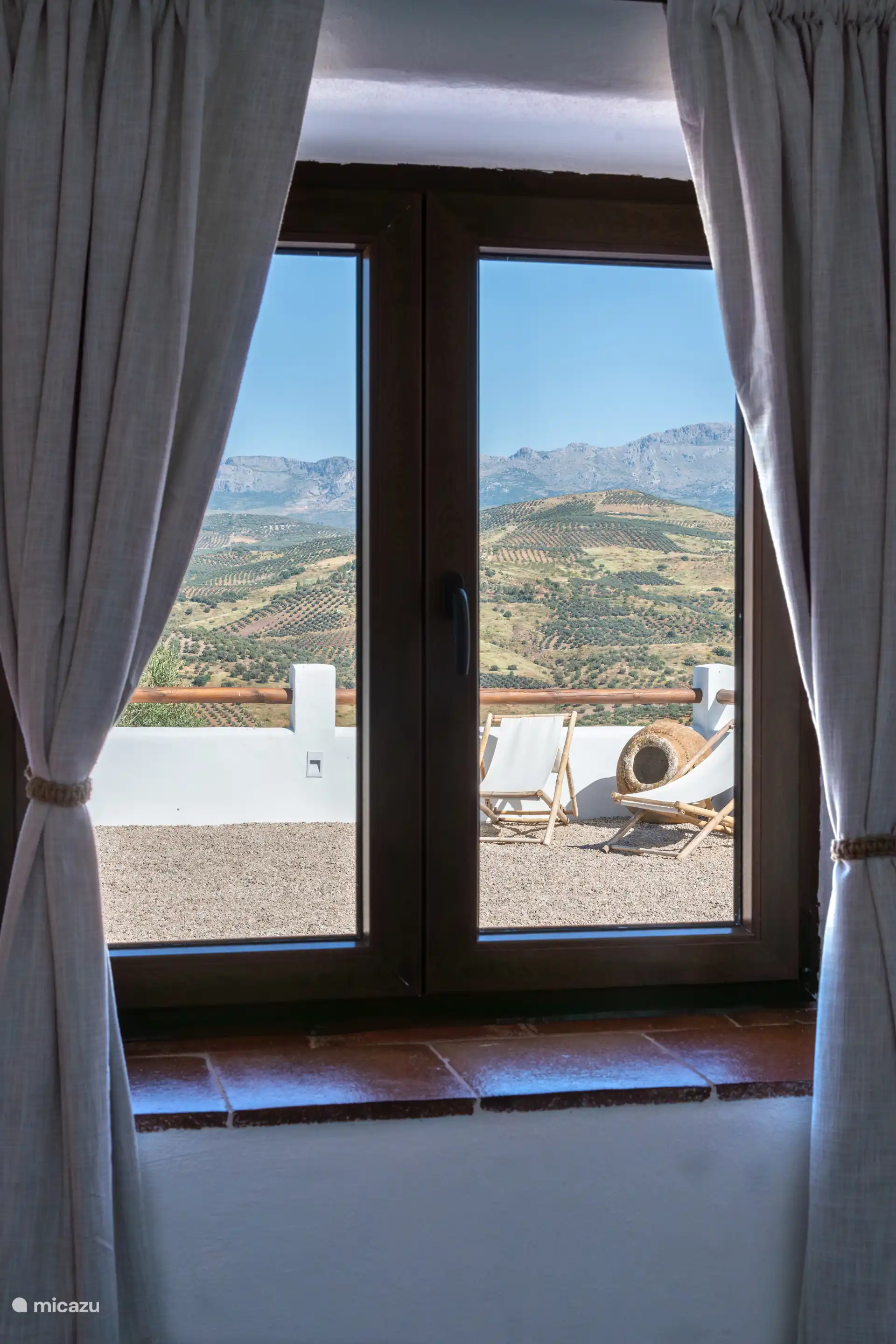 Uitzicht vanuit de secundaire slaapkamer naar het terras en het gouden landschap van de olijfgaarden bij zonsondergang