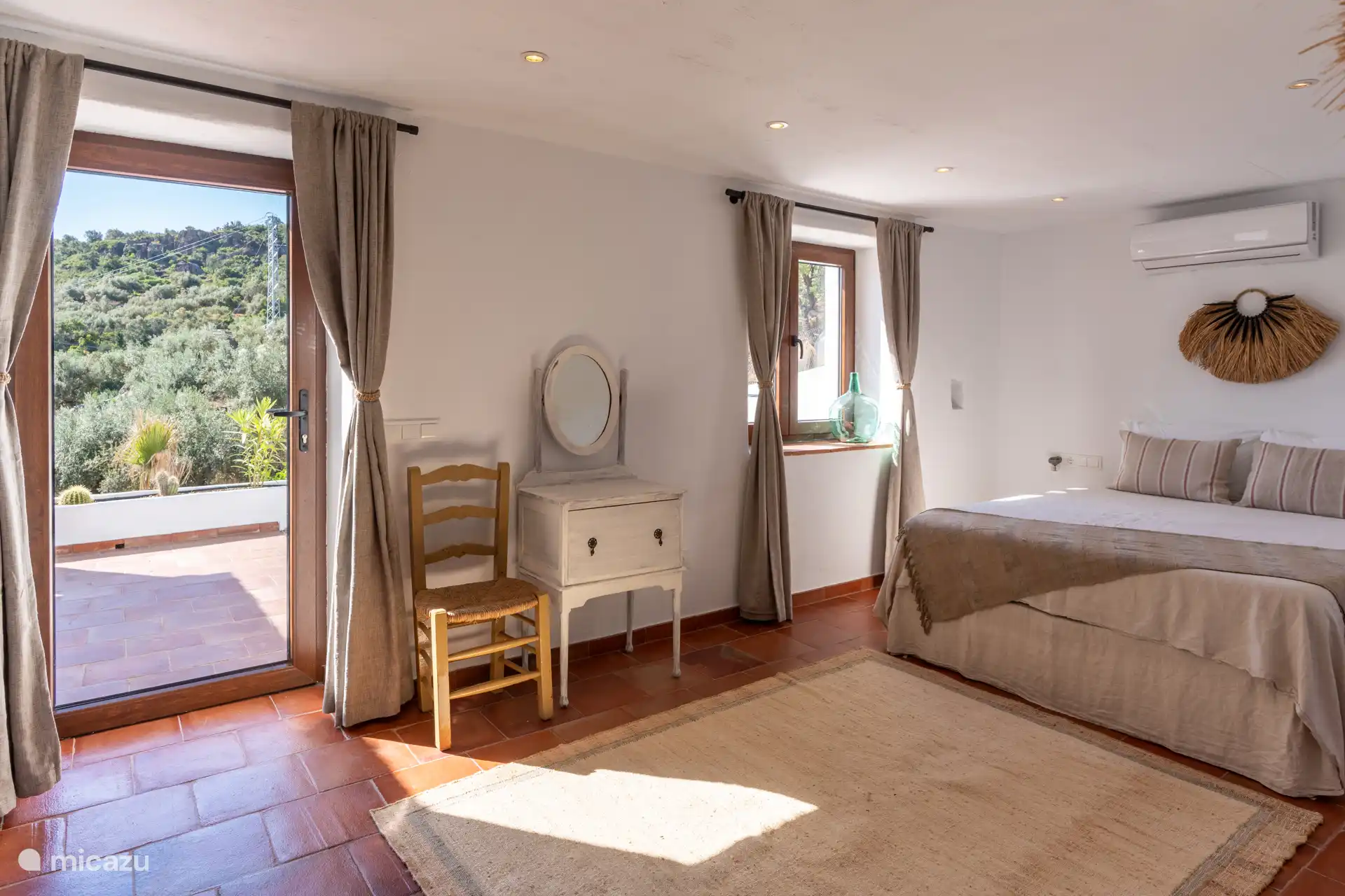 Hoofdslaapkamer met ramen van vloer tot plafond en toegang tot het terras, waar u kunt genieten van de zonsopgang en elk rustiek detail