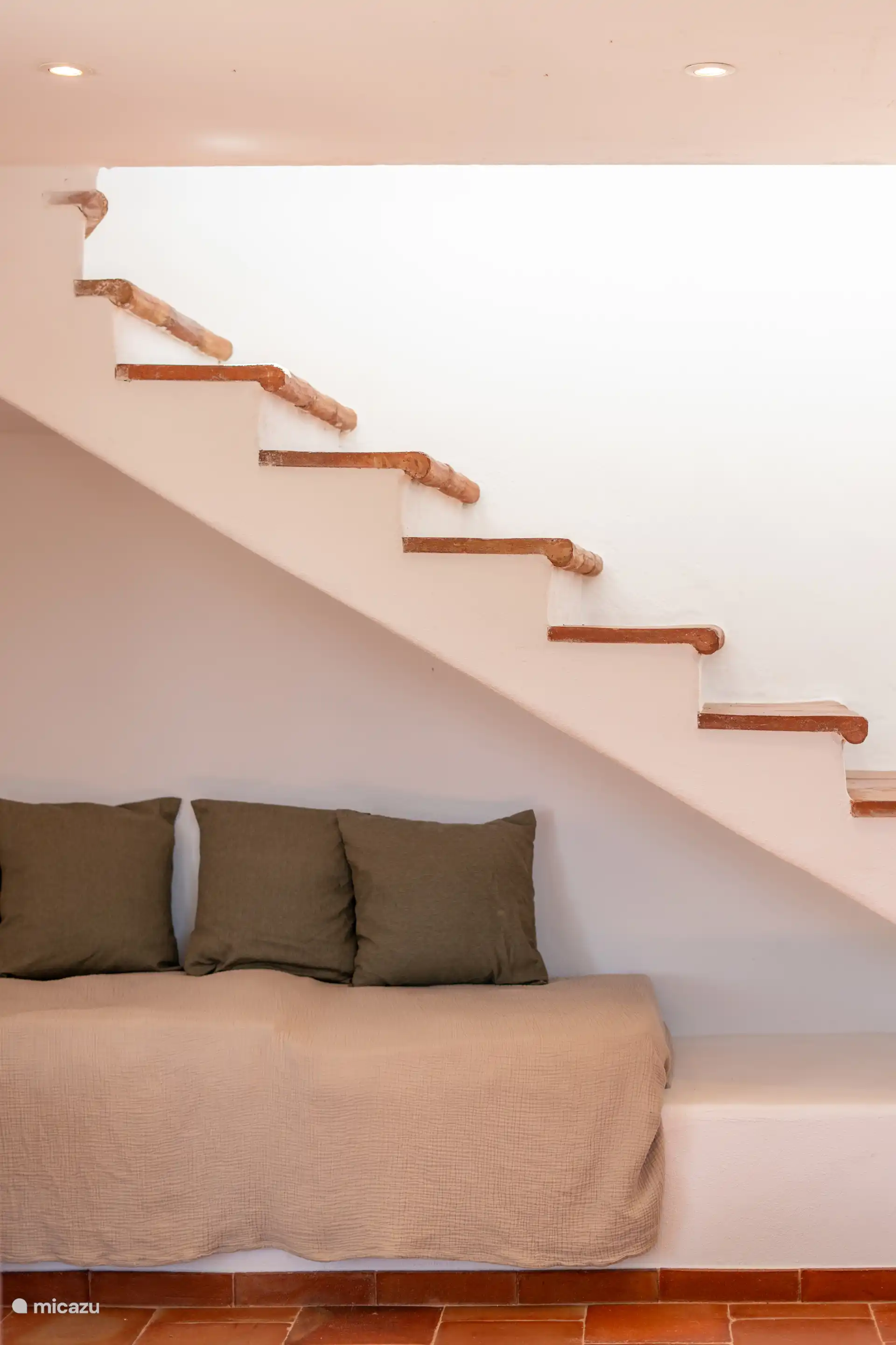 Gezellige bank gelegen onder de trap van kleitegels, een hoek met rustieke charme