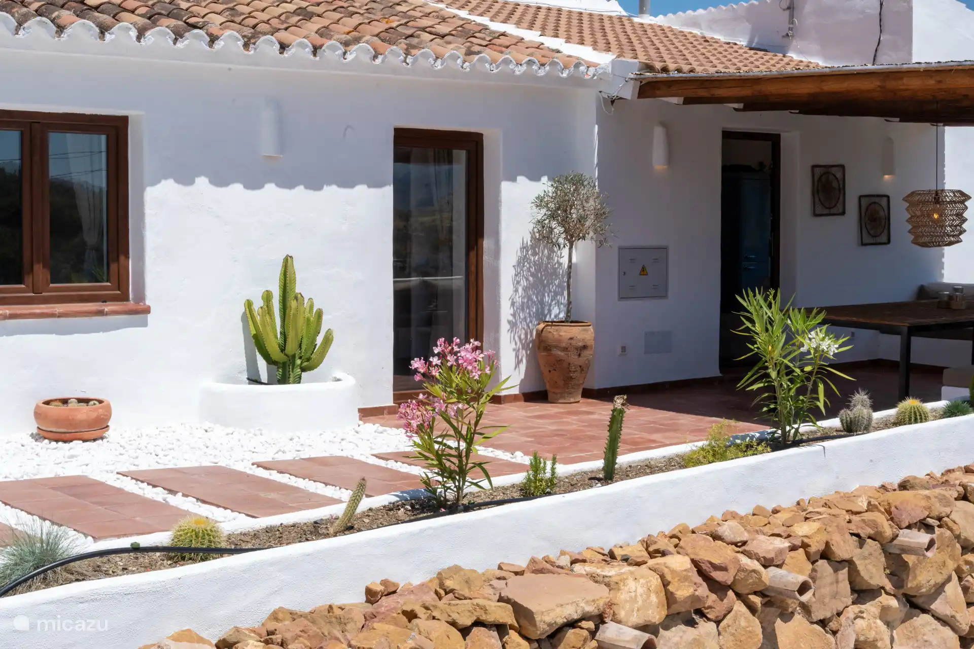 Gezellige entree met typische tegels, terracotta vloer en terras dat de gevel bekroont