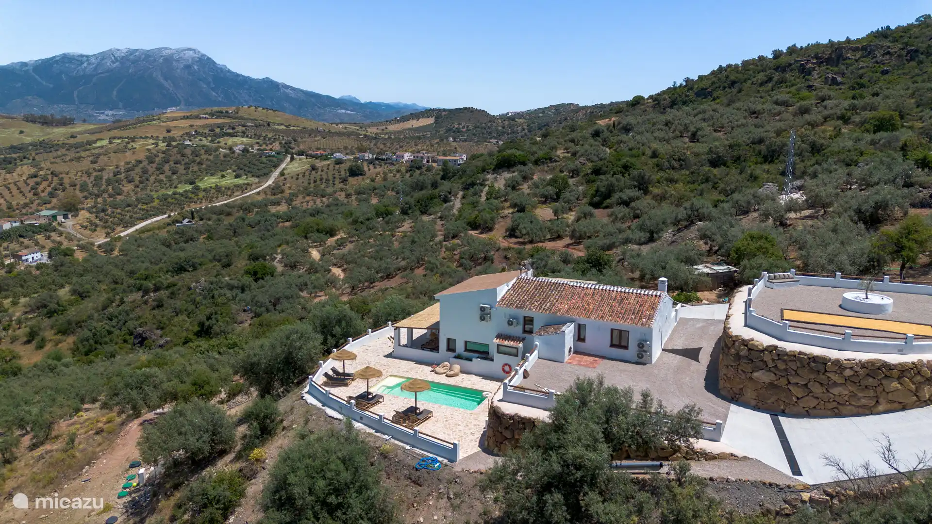 Luchtpanorama met het huis, het zwembad en de met sneeuw bedekte berg van La Maroma op de achtergrond