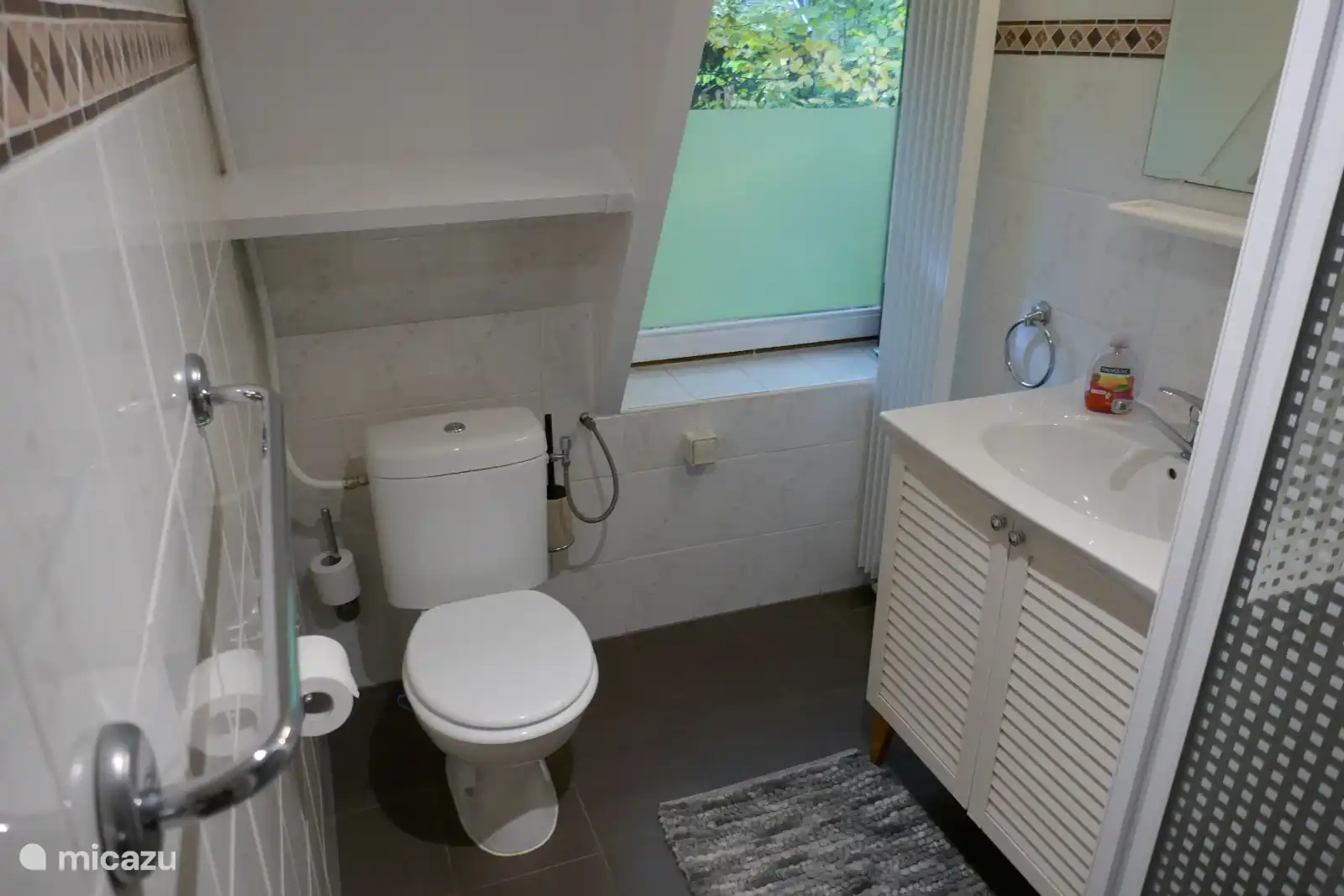 Frisches Badezimmer mit Tageslicht, WC, Waschbecken und Spiegel. Kompakt und komfortabel für einen erholsamen Aufenthalt.