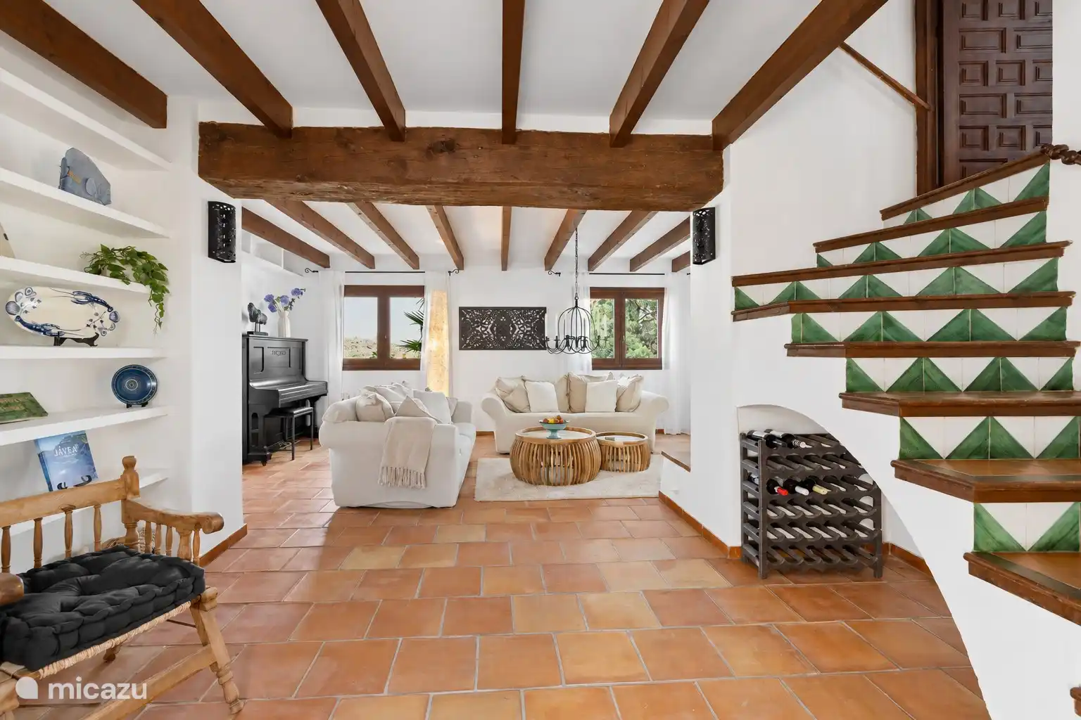 Le salon dispose d’un canapé de 2 places et demie et d’un canapé de deux places, avec le passage vers le logia à gauche et les escaliers carrelés verts à droite menant à la chambre Altea.