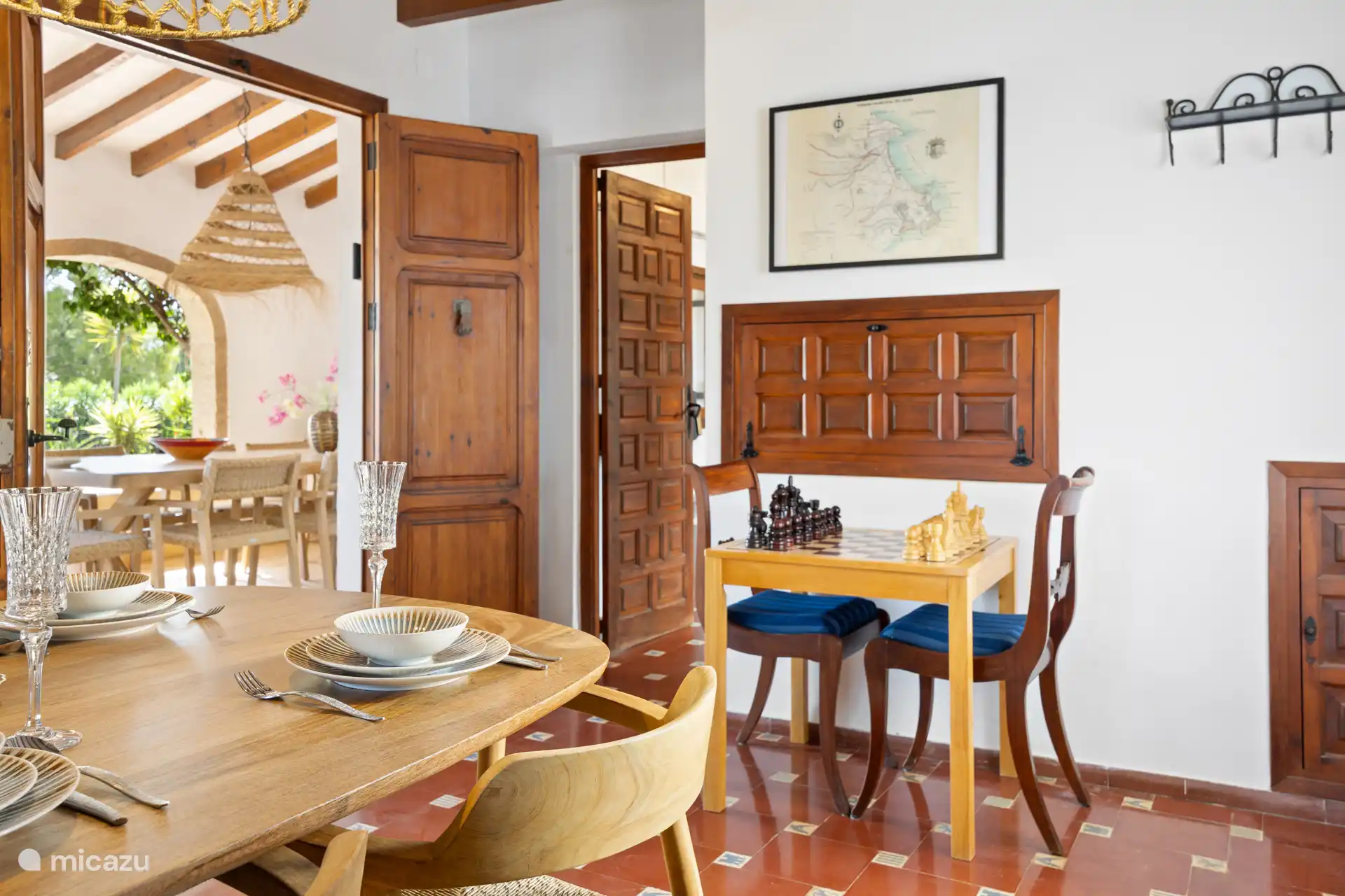 Salle à manger avec une grande table pour 8 personnes. De plus, il y a une table d’échecs avec deux chaises. Le sol authentique carrelé espagnol et la vitrine avec vaisselle créent une belle ambiance.