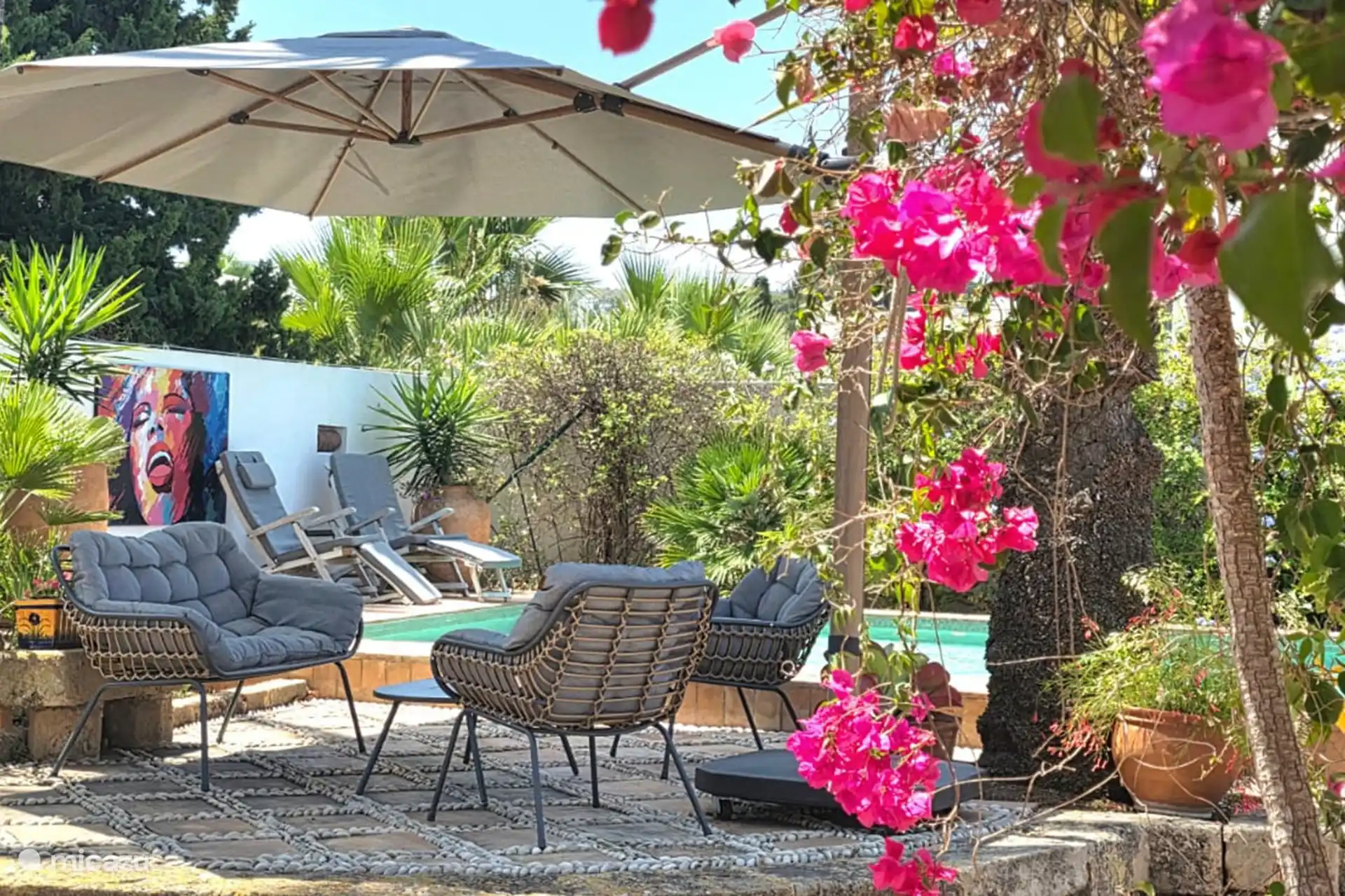 Espace salon avec un grand parasol près de la piscine. 