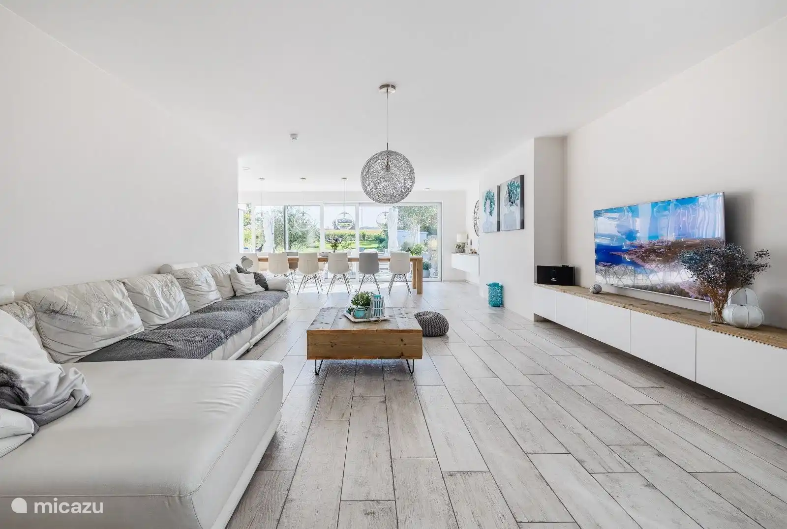 Gran salón abierto de 105m² con techos altos y grandes ventanales correderos para obtener la máxima luminosidad. Vista del jardín orientado al sur.