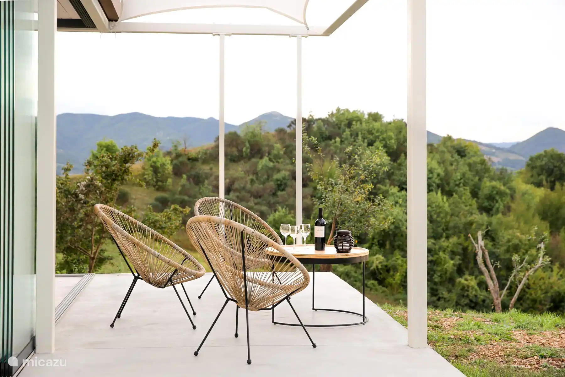 Un apéritif au coucher de soleil avec vue sur la vallée, lumière chaude et sièges confortables.