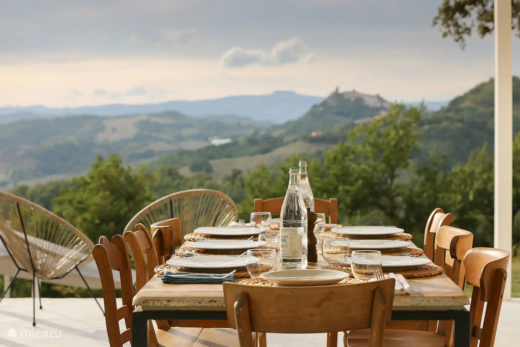 Ein rustikal-schicker Außen-Esstisch für gemeinsame Mahlzeiten gedeckt und bietet einen atemberaubenden Panoramablick auf die Hügel.