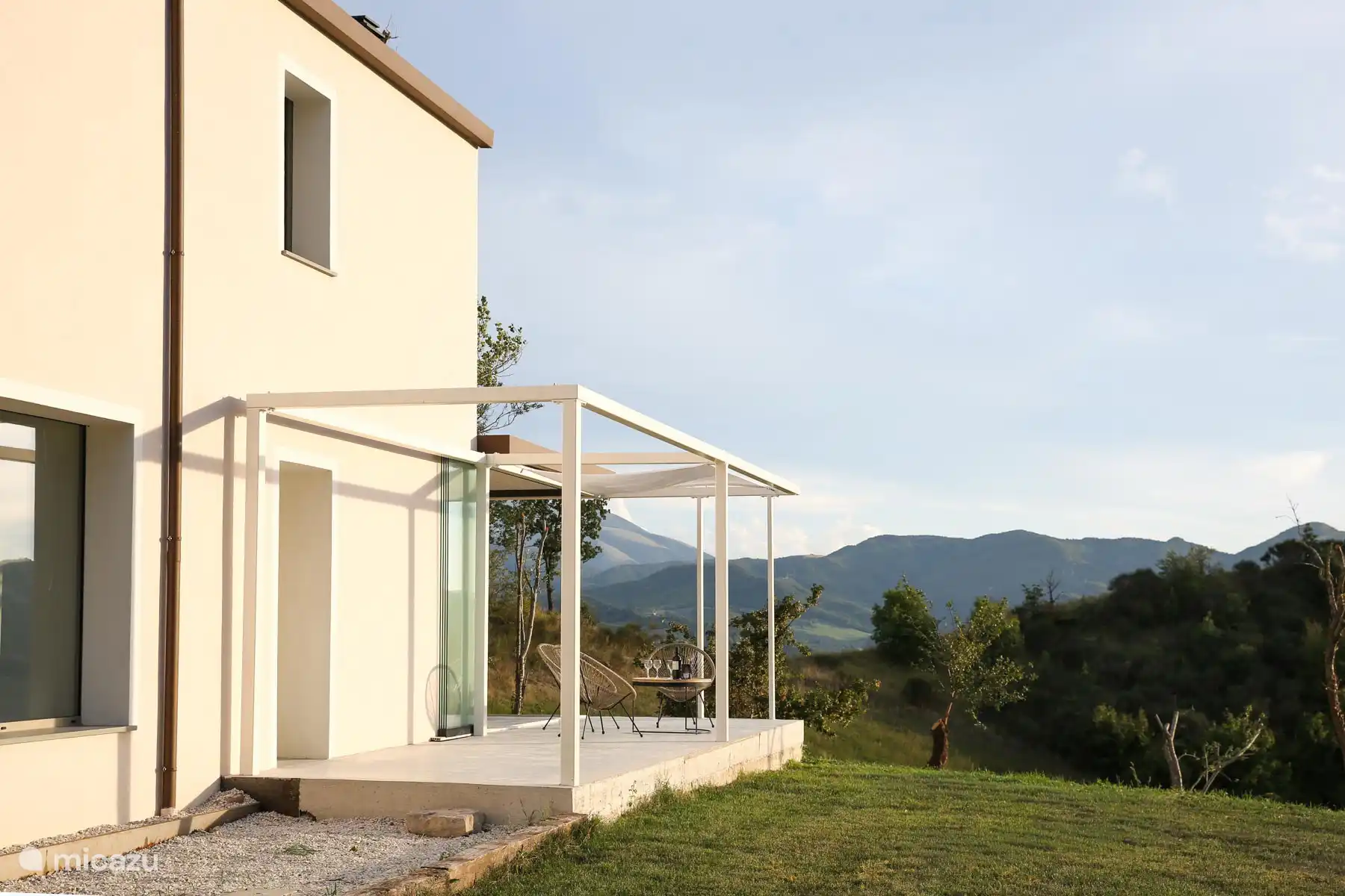 Un apéritif au coucher de soleil avec vue sur la vallée, lumière chaude et sièges confortables.