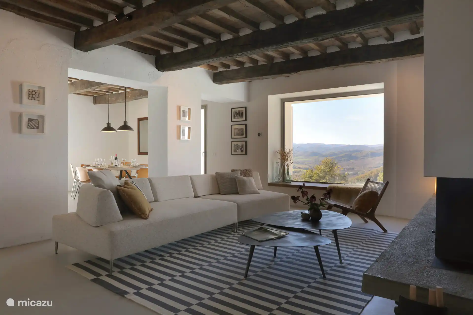 Zwei deutlich markante rustikale-moderne Wohnbereiche, hervorgehoben durch freiliegende Holzbalken, Stein-/Ziegelwände und einen zeitgenössischen Kamin. Beide Räume bieten einen großartigen Panoramablick durch große Fenster.