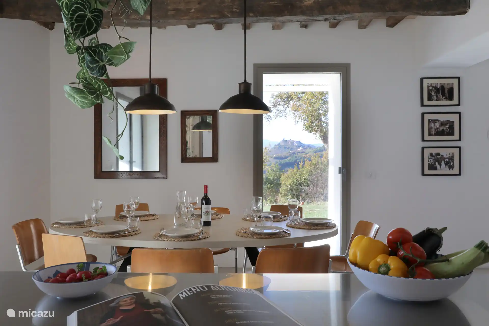 Eine moderne, offene Küche/Esszimmer mit zentraler Insel, dunklen Holzverschlüssen und rustikalen freiliegenden Balken, perfekt für das Gemeinschaftsleben.