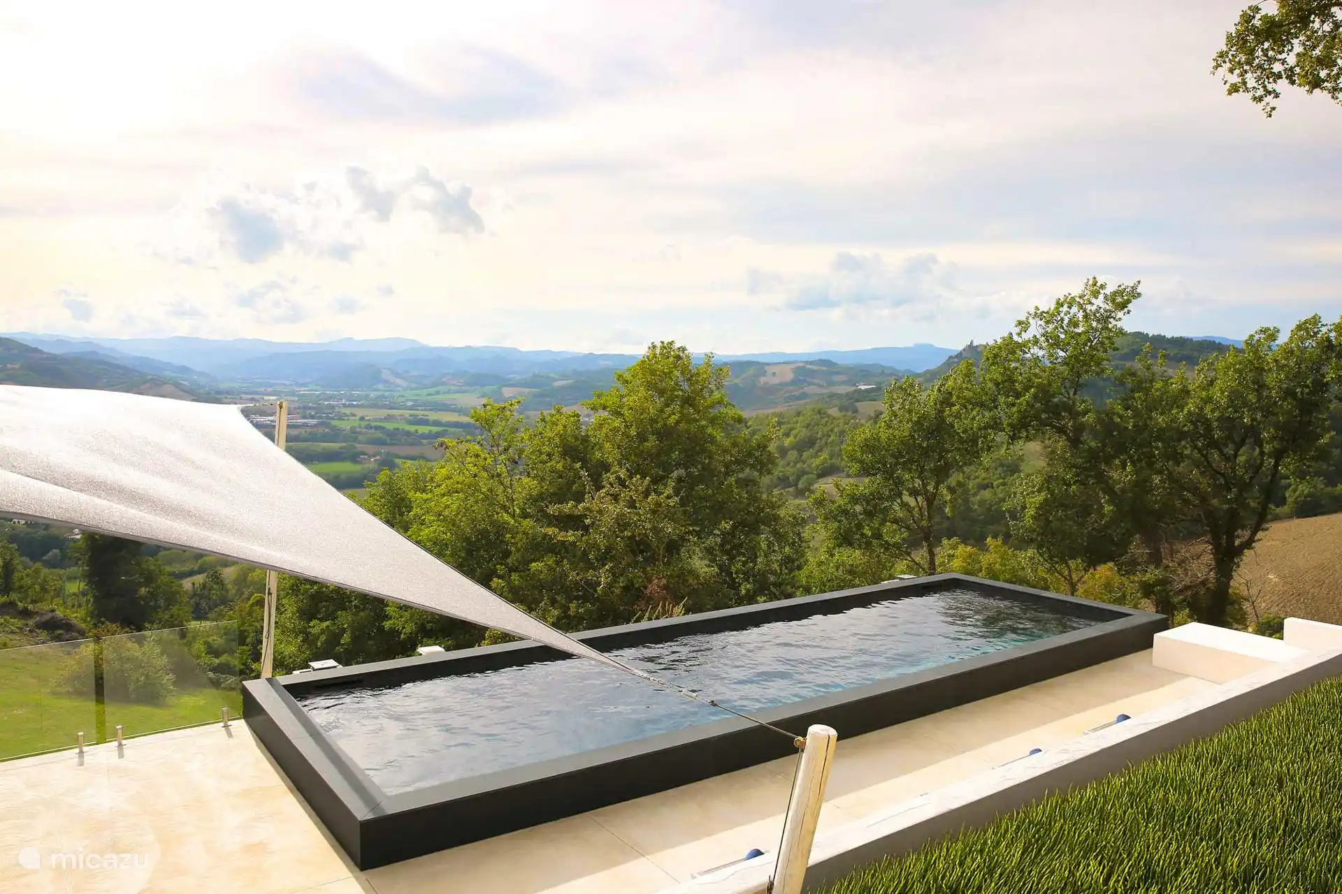Modern rechthoekig zwart bassin met een panoramisch zonneterras met uitzicht op de heuvels, met spectaculaire uitzichten op de Apennijnen.